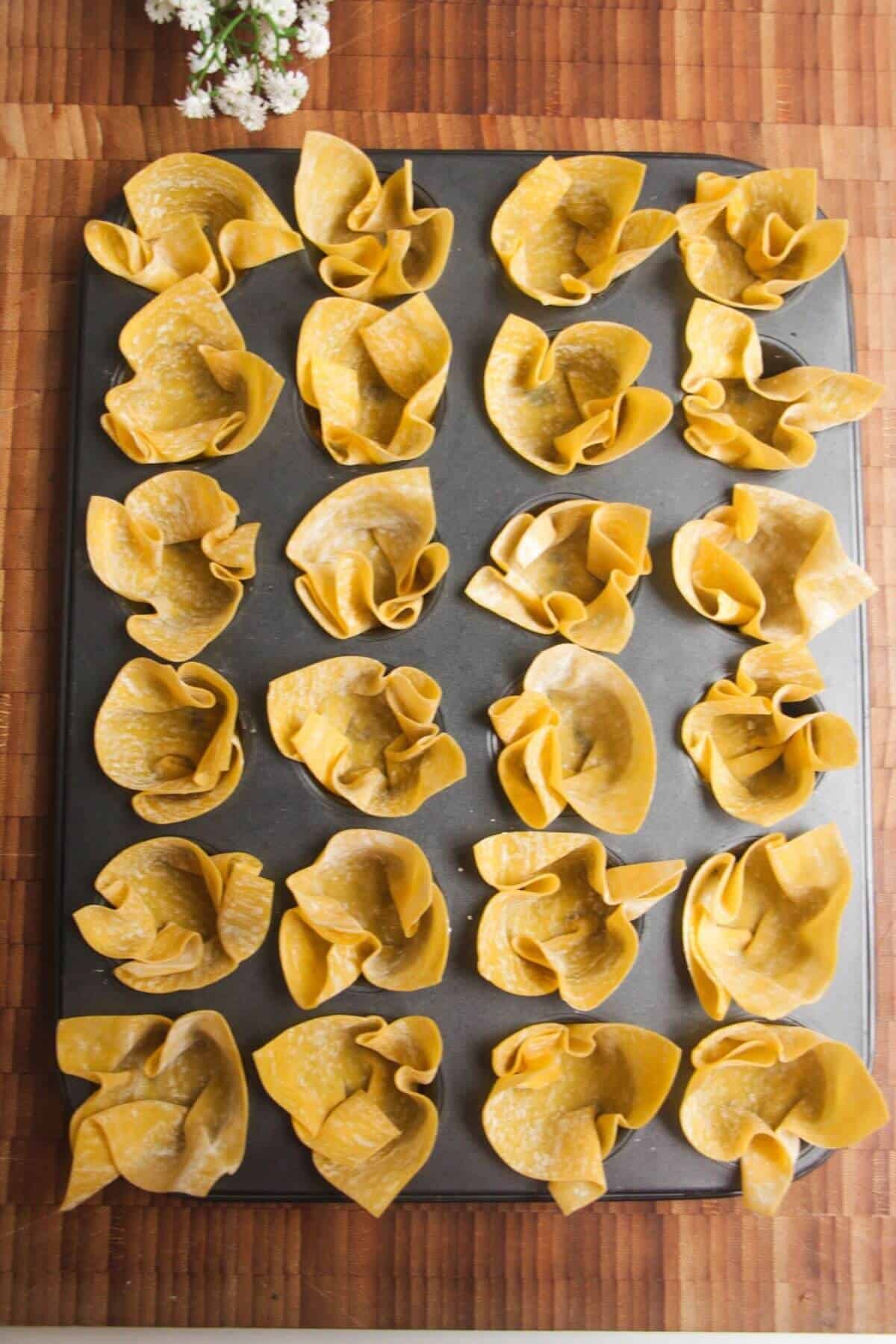 Wonton wrappers pressed into mini muffin tin.