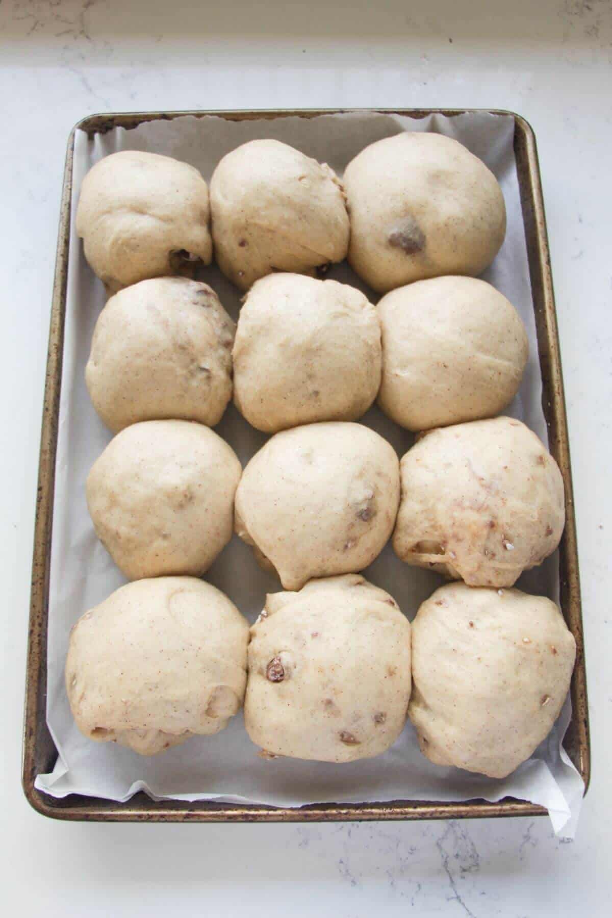 12 mini egg hot cross buns after rising in a baking paper lined oven tray.