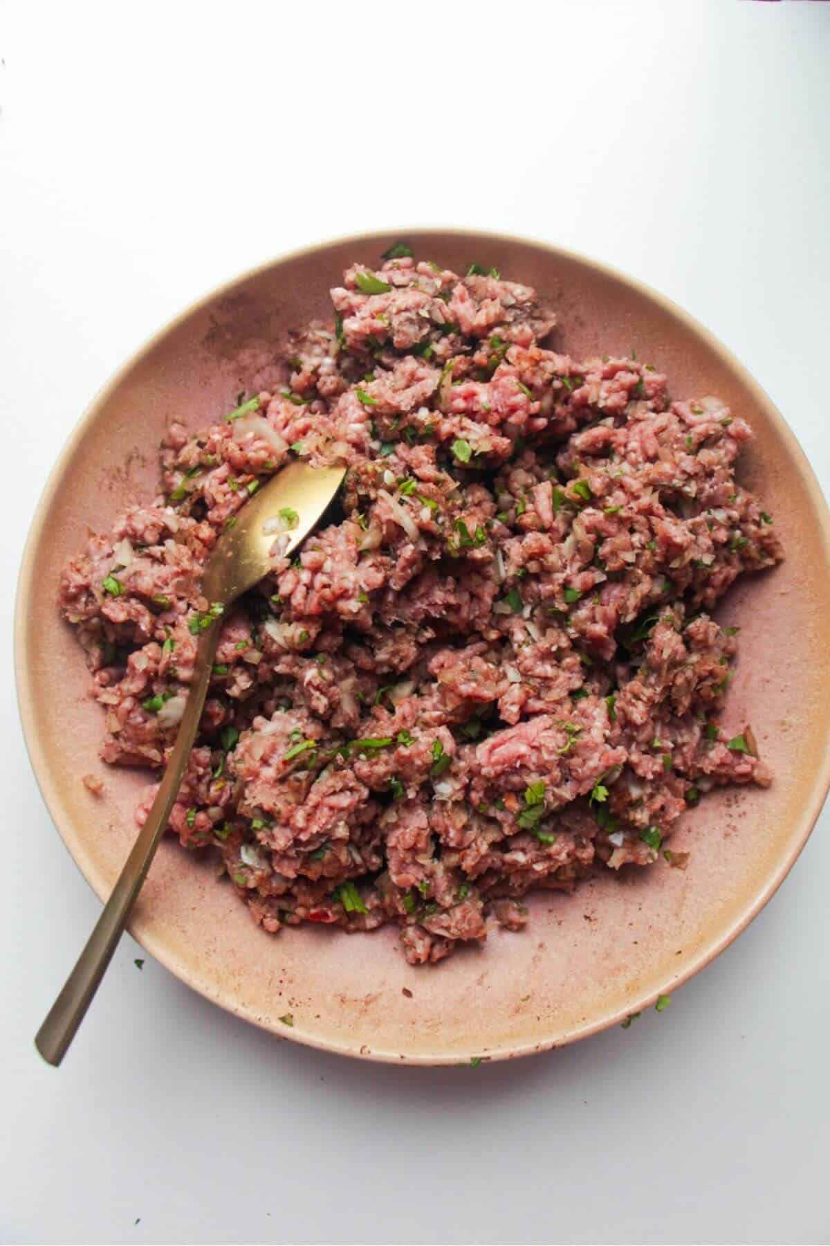 Meatball ingredients mixed in a pink bowl.