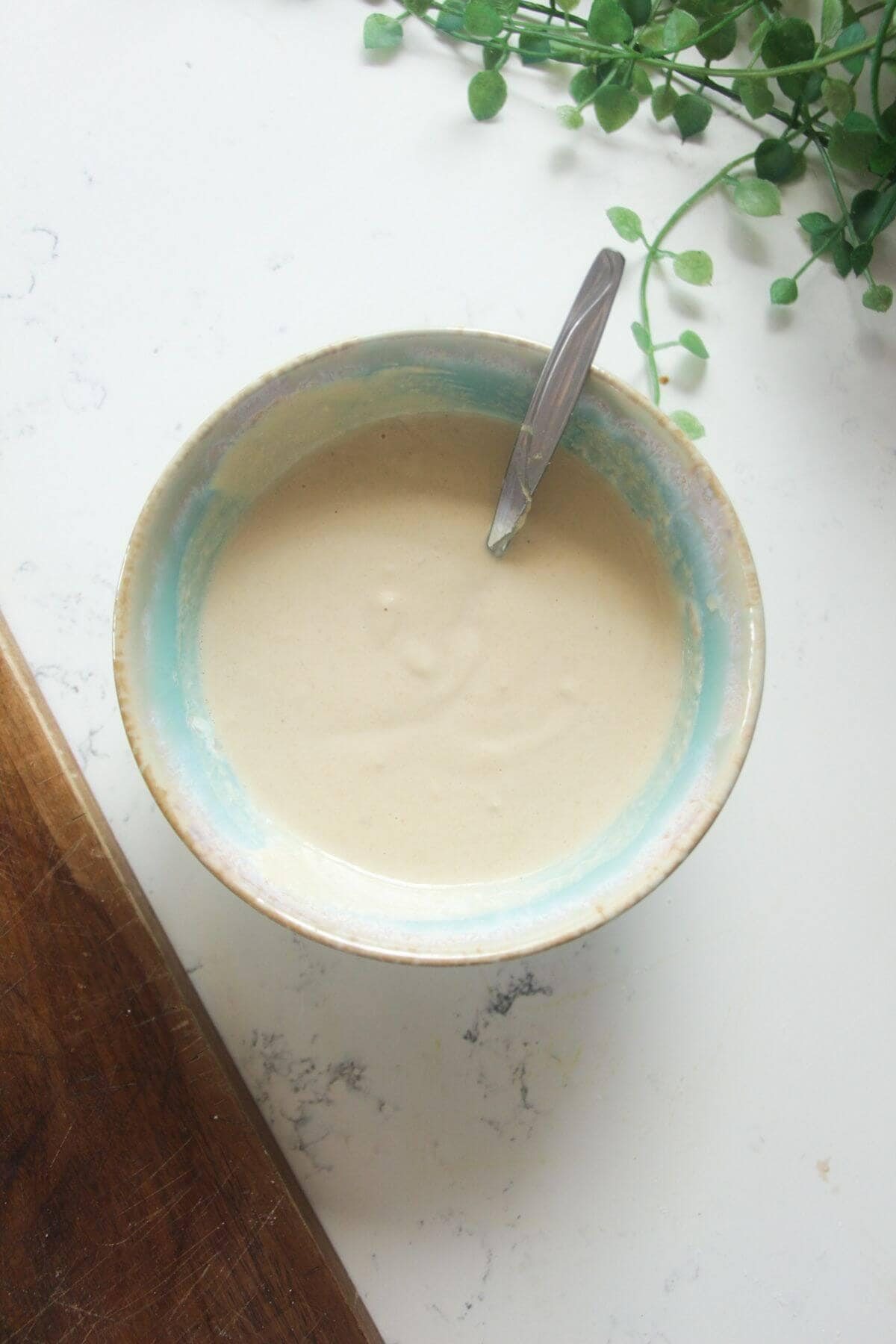 Garlic tahini dressing in a small blue bowl.