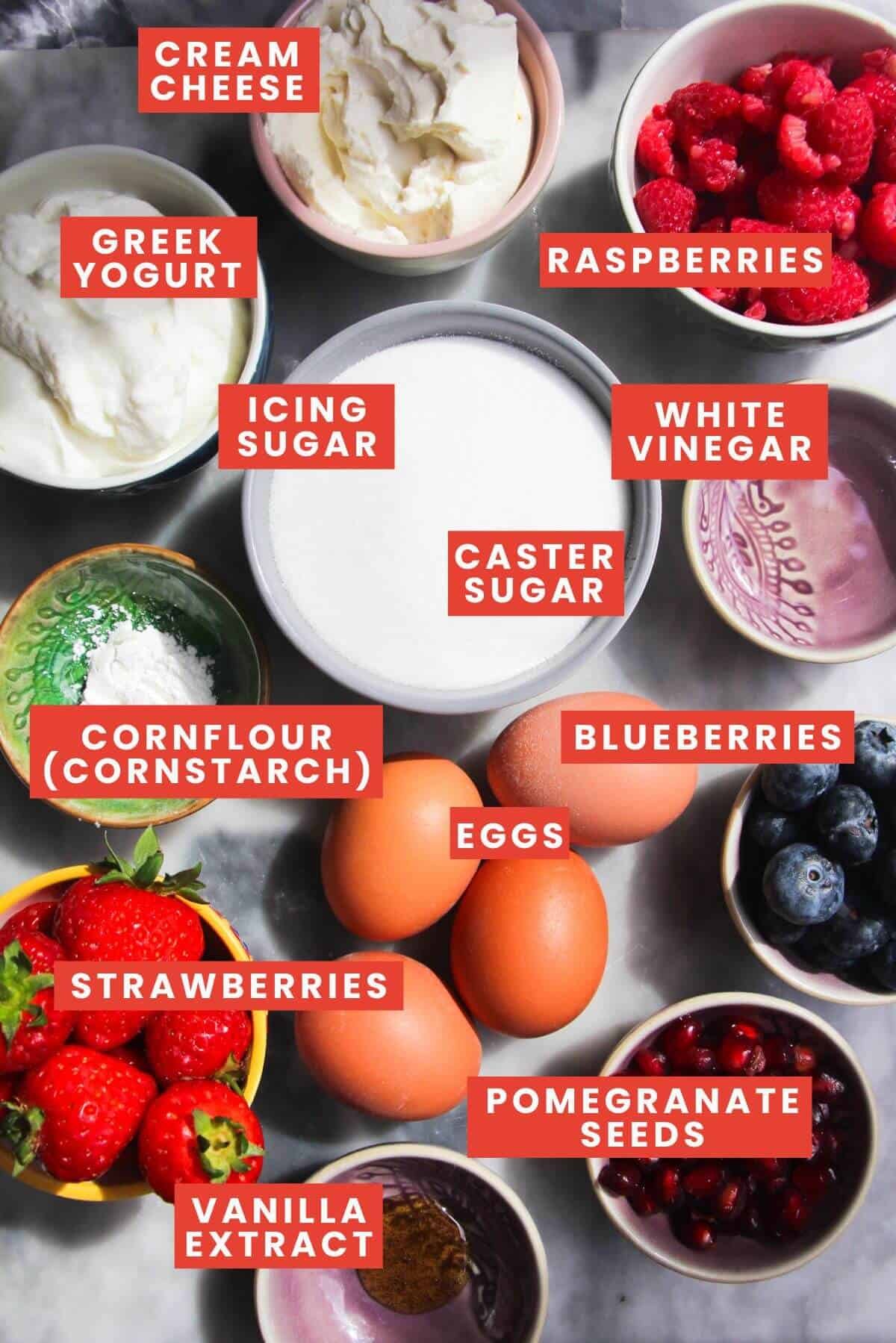 Ingredients for mini pavlovas laid out on a grey marble background and labelled.