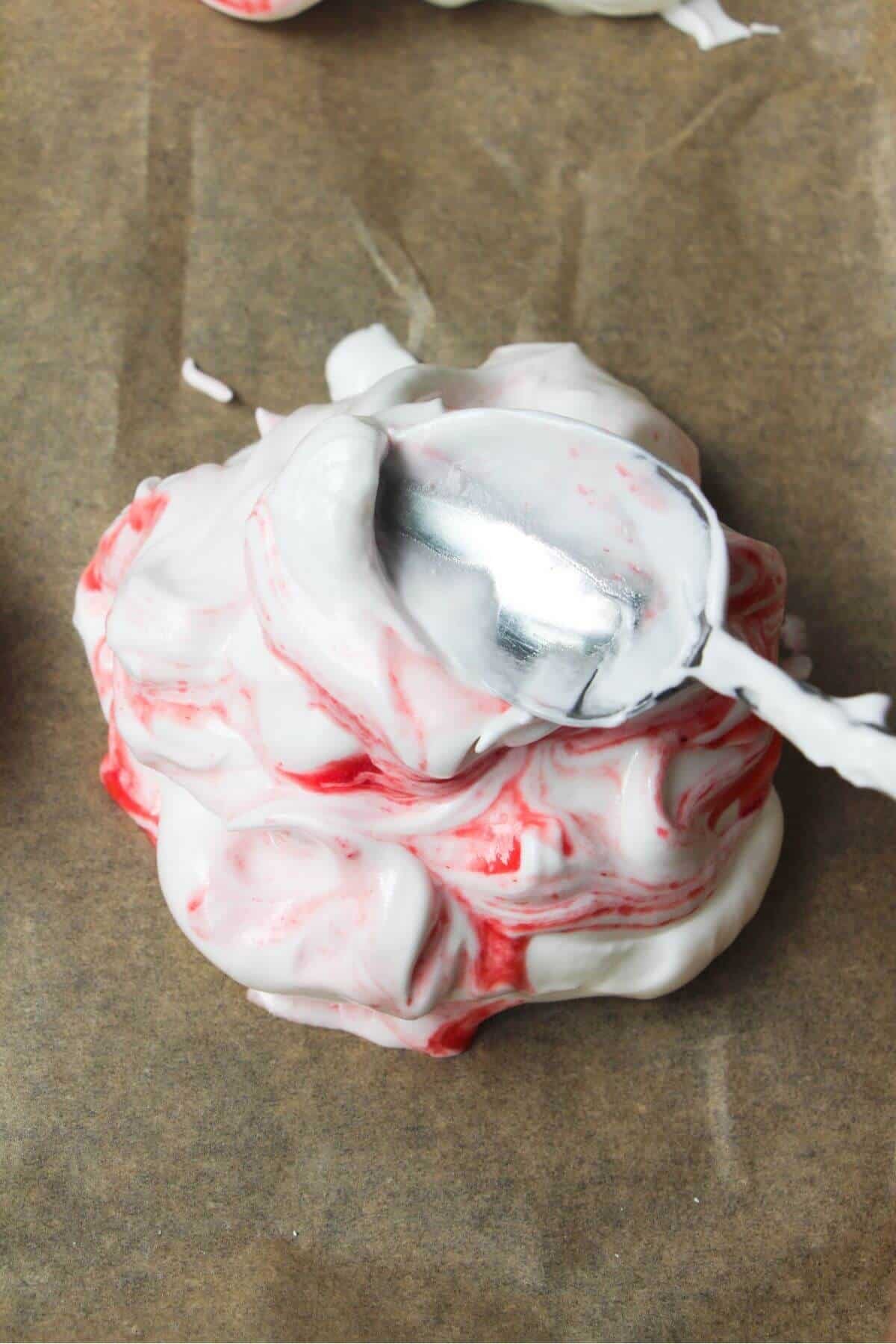 Silver spoon creating crater in the top of a mini pavlova.