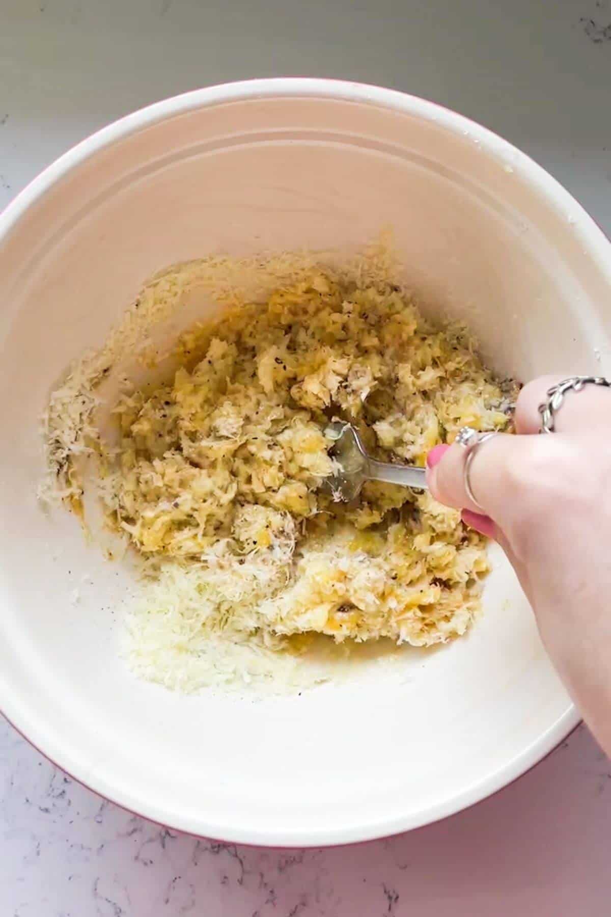 Fork mixing cheese, miso and eggs in a bowl.