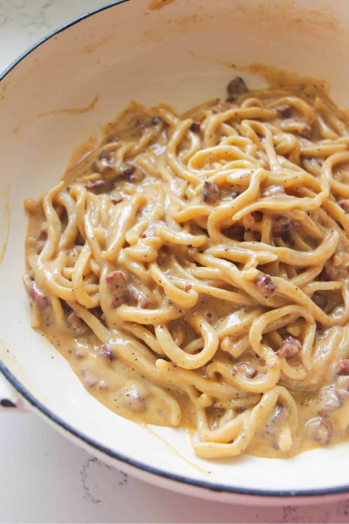 Creamy spaghetti carbonara in a white pan.