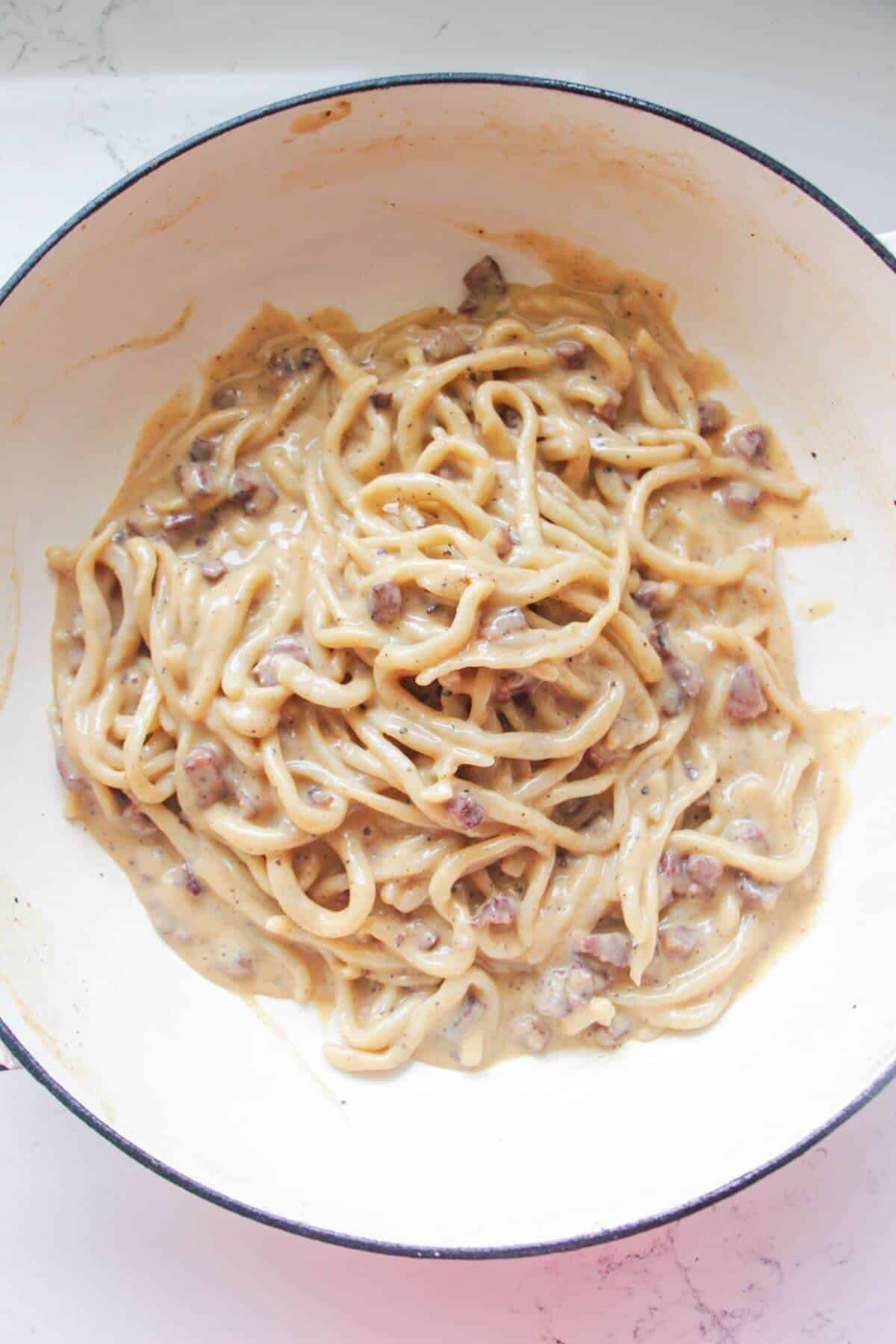 Creamy spaghetti carbonara in a white pan.