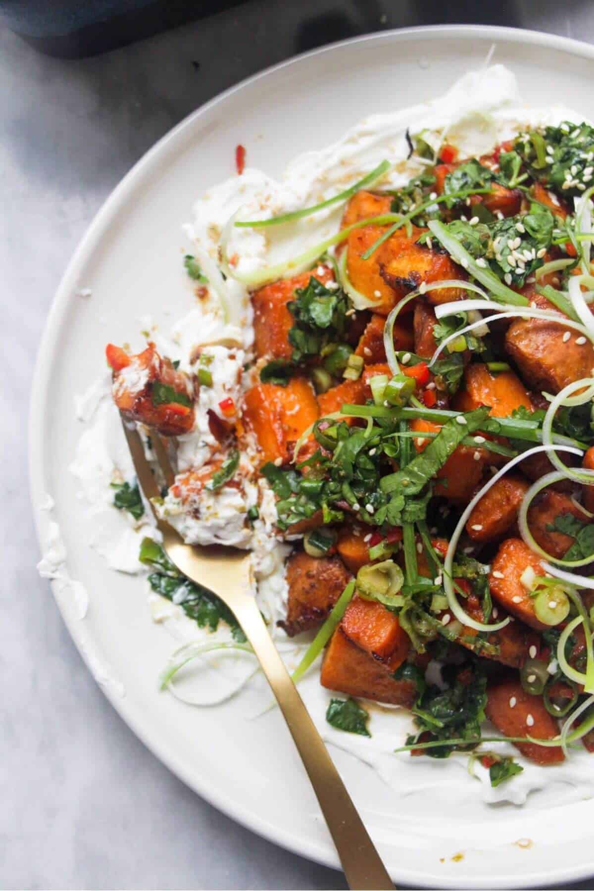 Close up of miso sweet potatoes on labneh, with a gold fork on the plate.