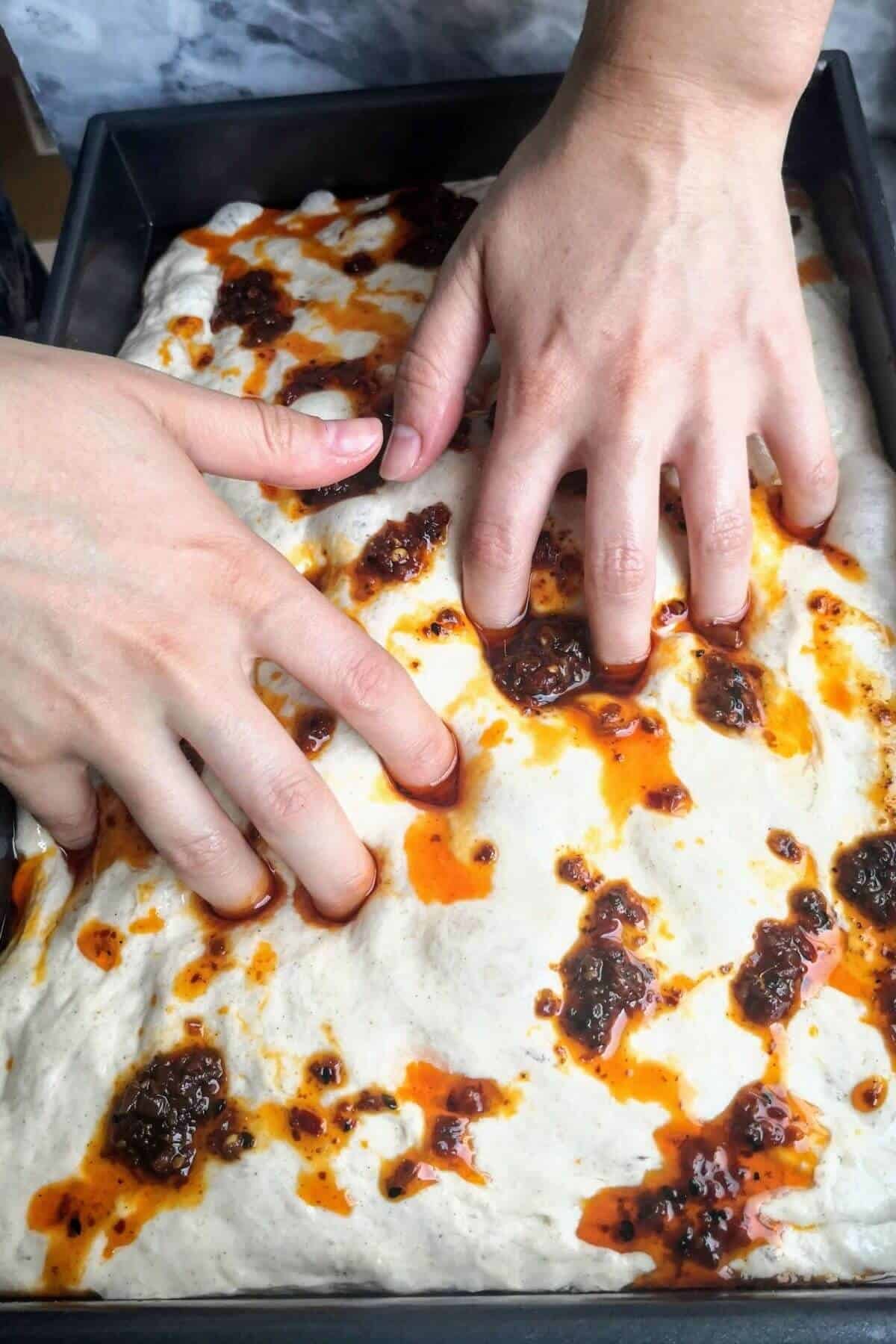 Fingers dimpling the no-knead focaccia.