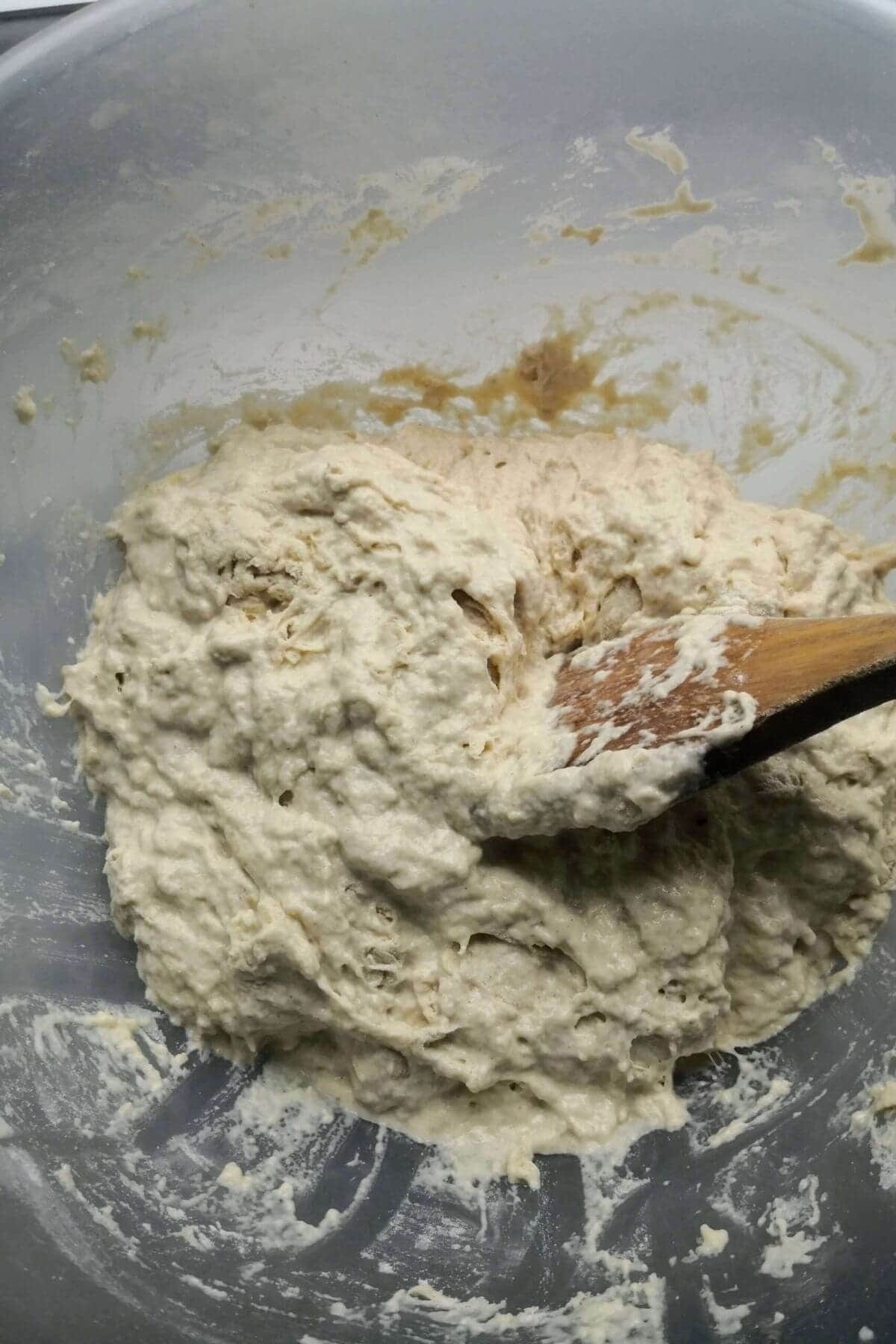 Foccacia dough after mixing with a wooden spoon in a large mixing bowl