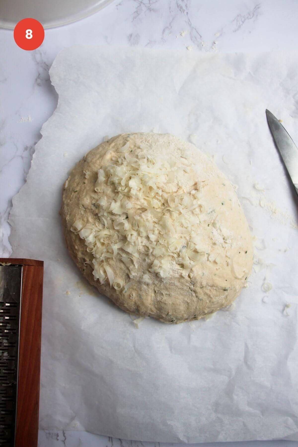 Grated parmesan cheese on top of shaped bread dough.