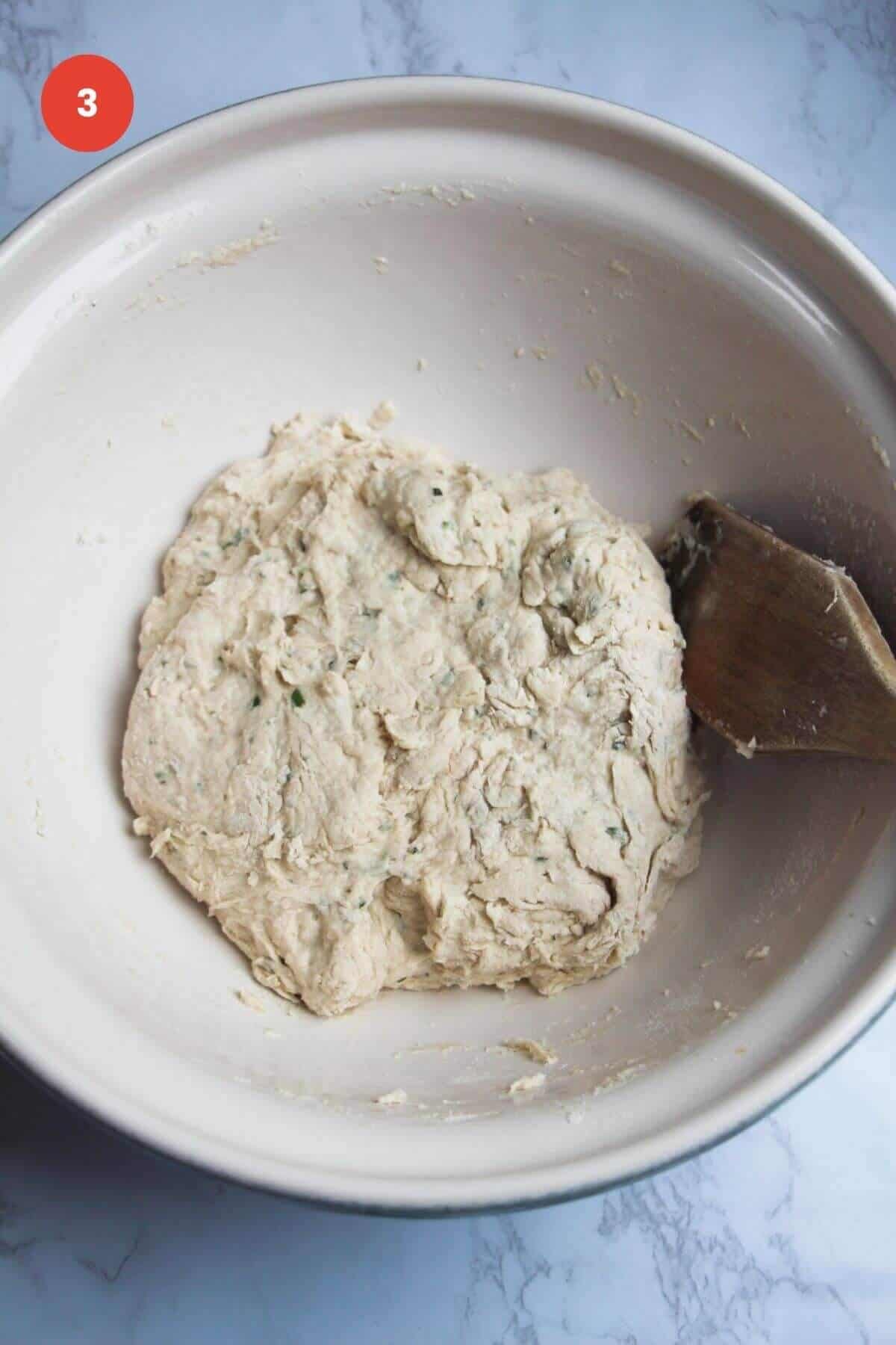 Rosemary parmesan bread dough in bowl.