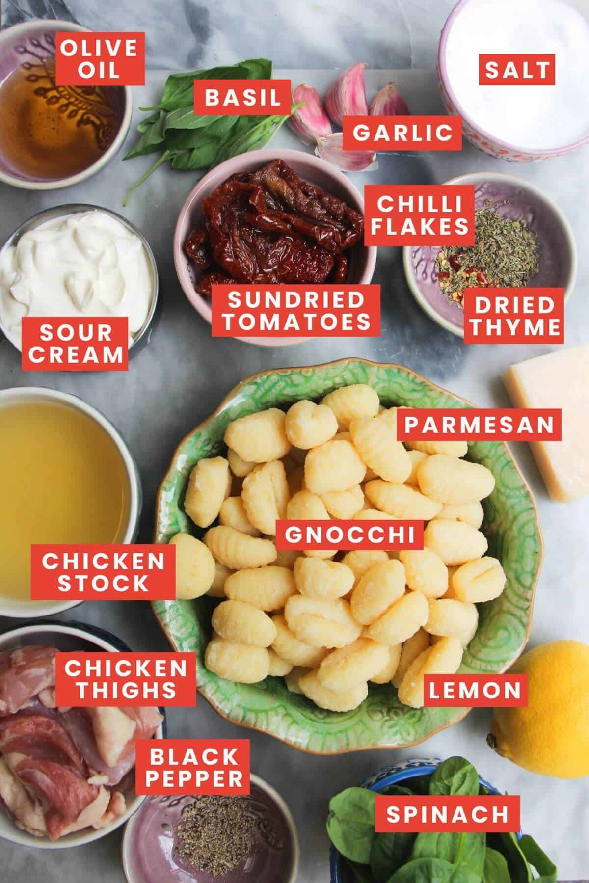 Ingredients for creamy chicken gnocchi laid out on a grey marble background and labelled.