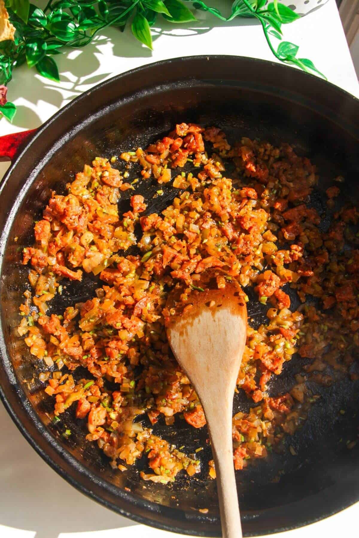 Chorizo cooking with onion and spices in a pan.