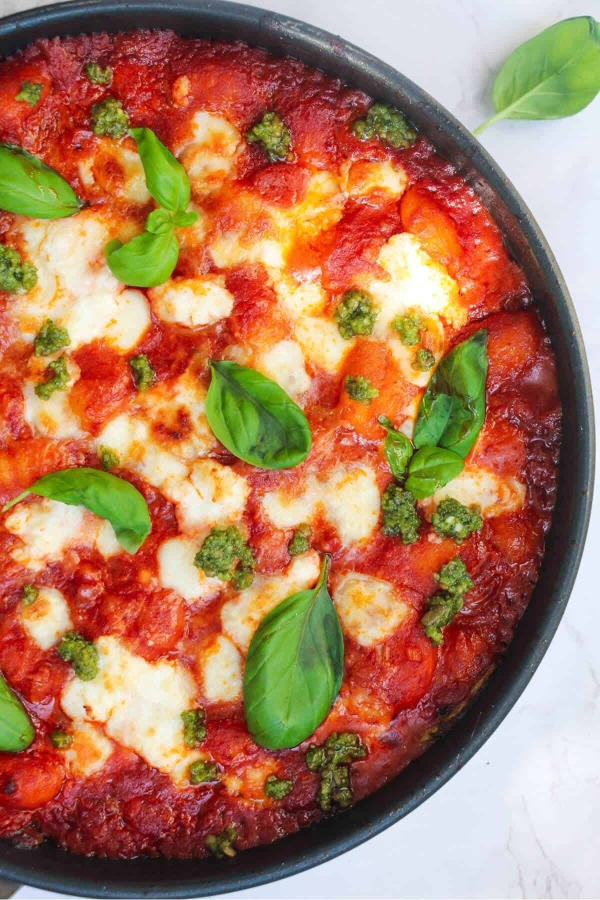 Mozzarella topped gnocchi alla sorrentina in a small frying pan, topped with basil leaves.
