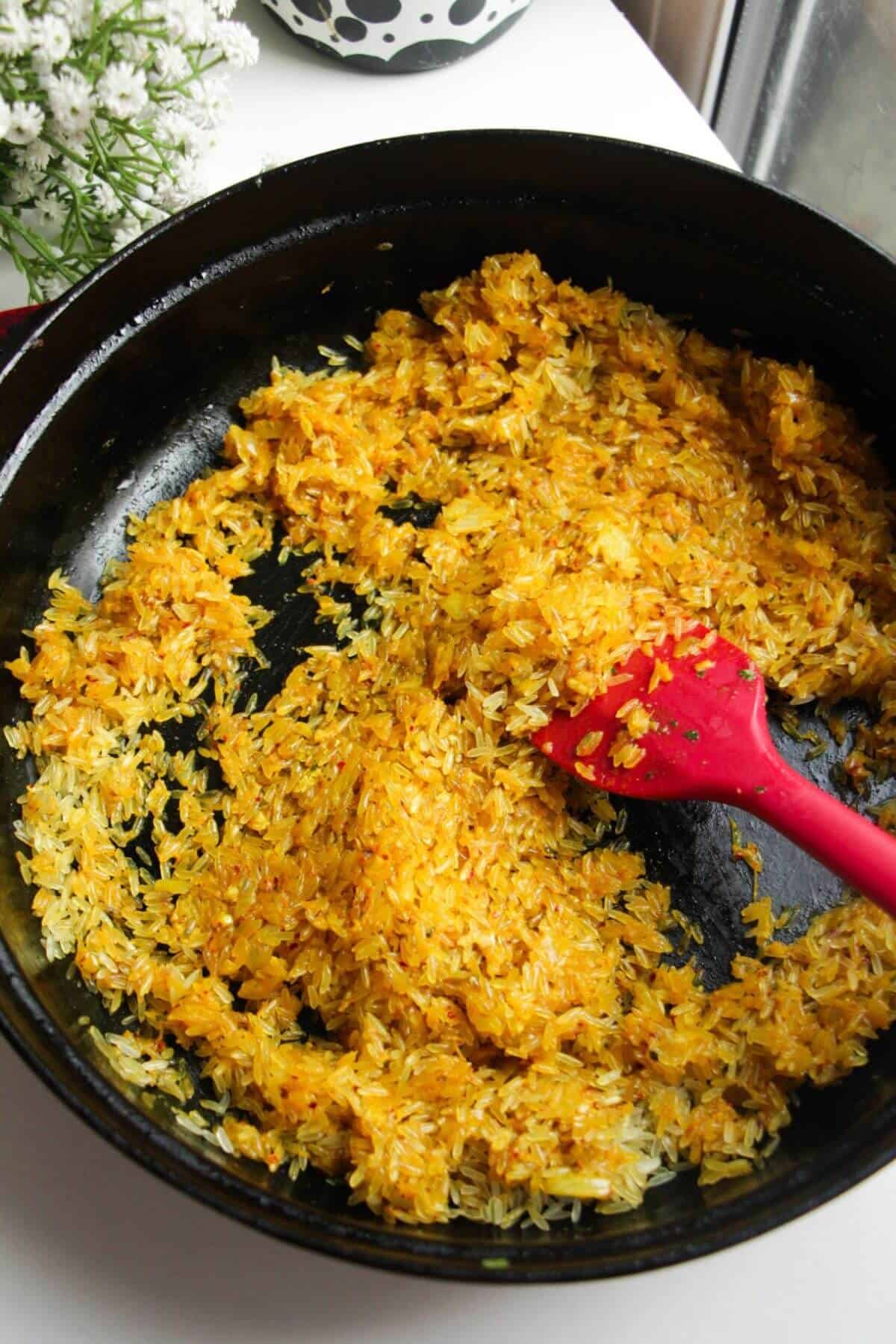 Stirring spices, onion and rice in a large pan.