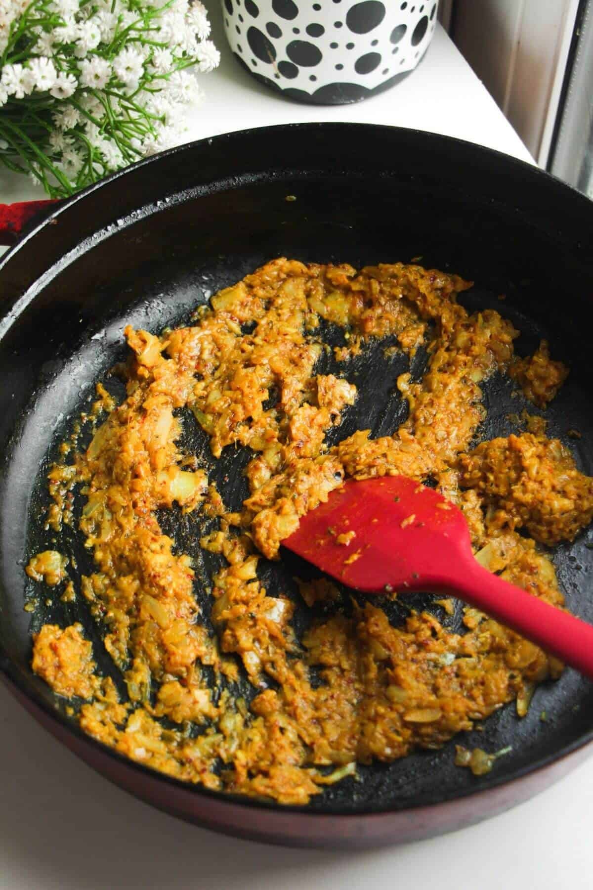 Cooking spices and onion in a large pan.
