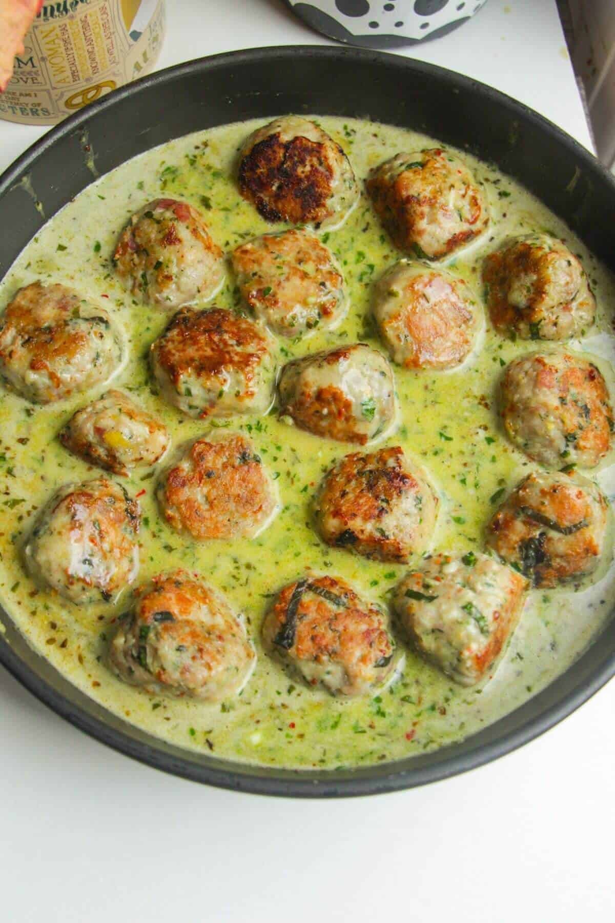 Browned meatballs added back into creamy pesto sauce.