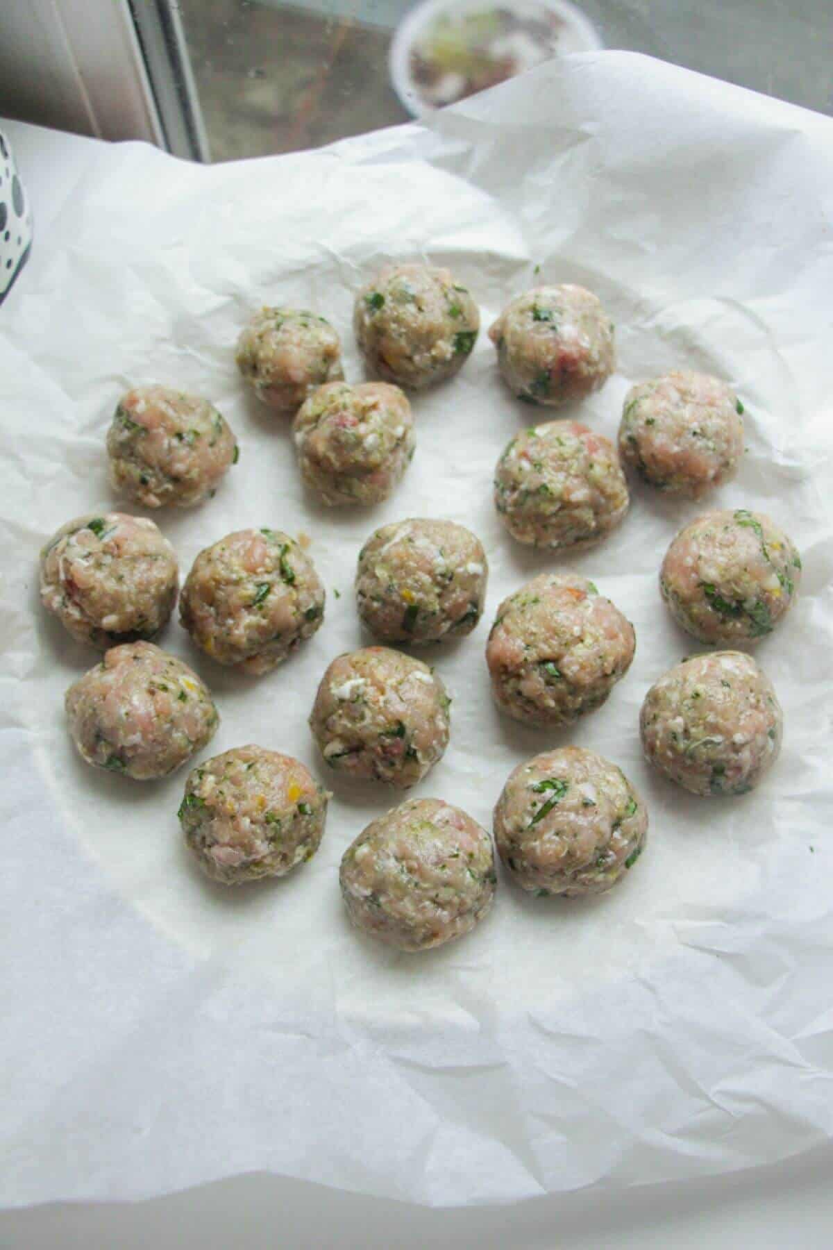 Rolled chicken and pesto meatballs on a lined plate.