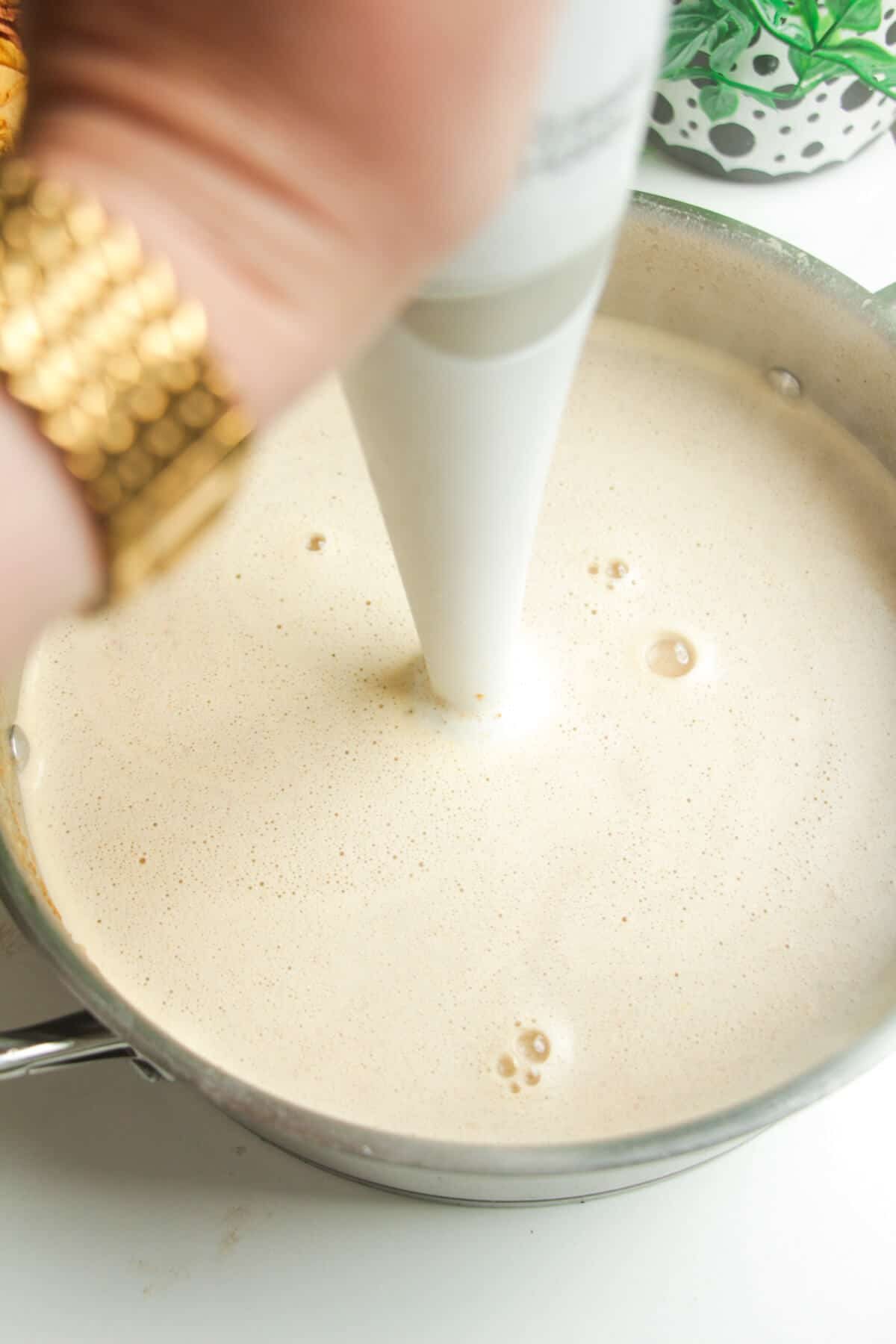 Immersion blender mixing white chicken chili.
