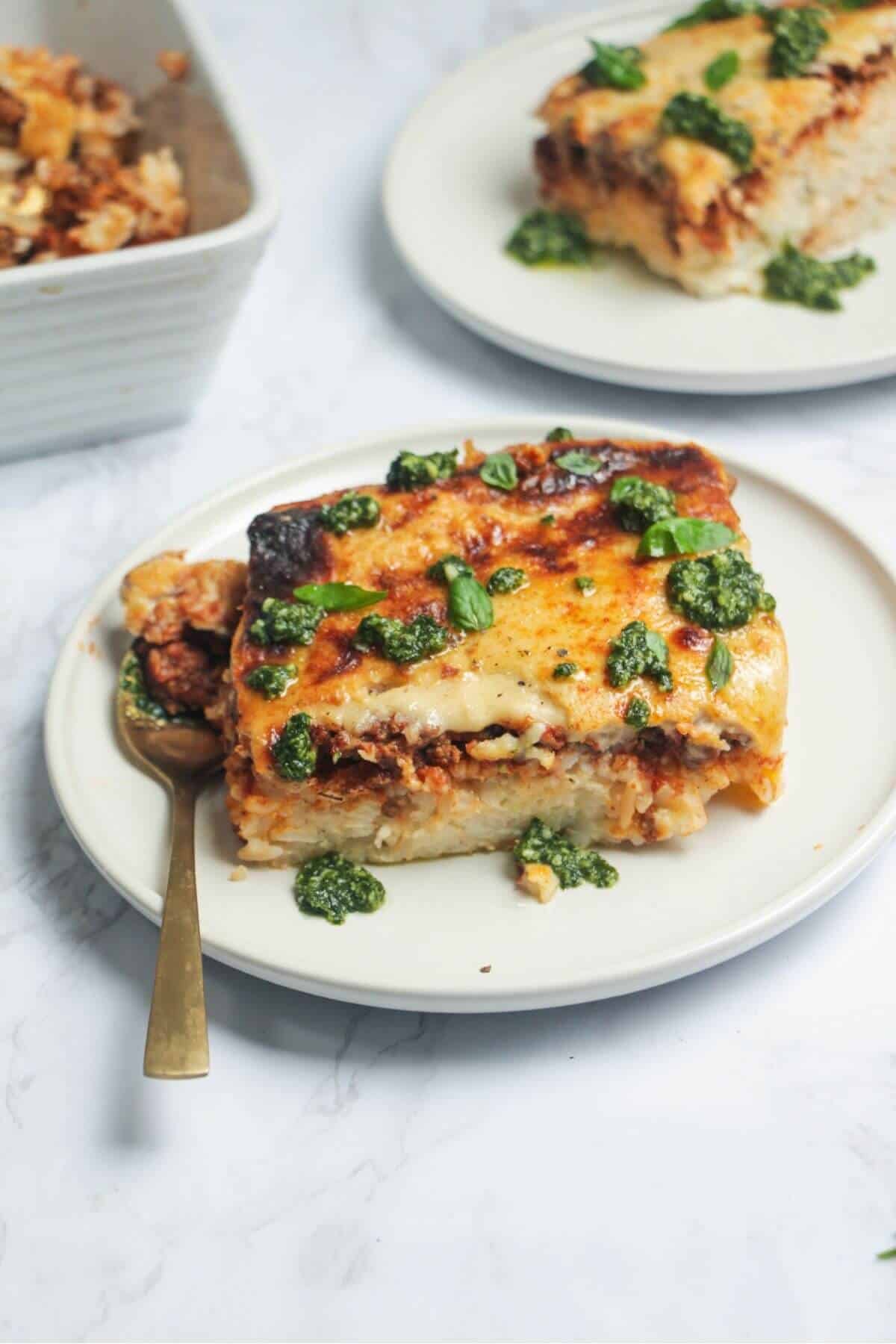 Bolognese Rice Bake on a small white plate, with another plate of the bake in the background.
