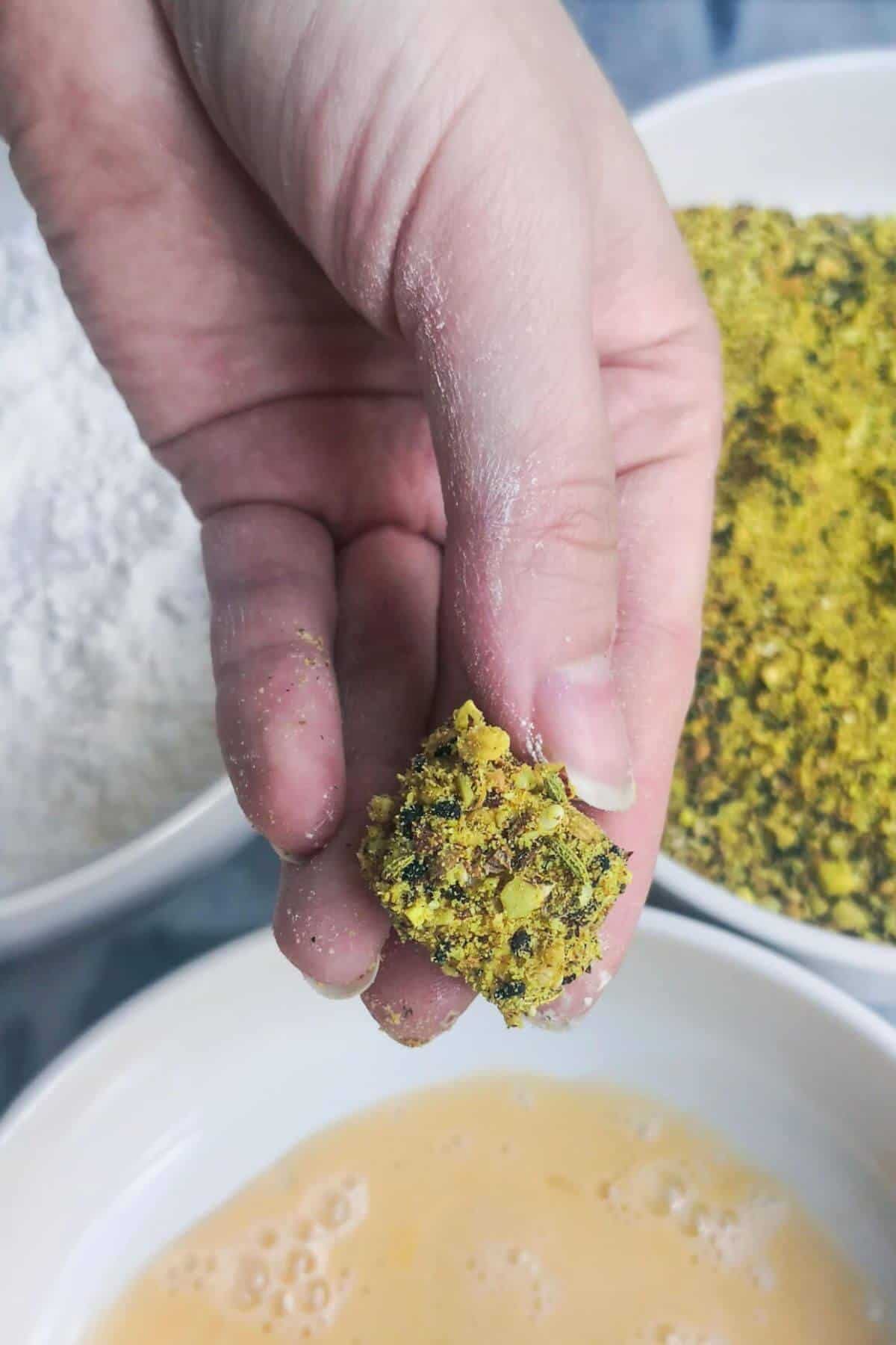 Hand holding up a dukkah crusted halloumi bite.