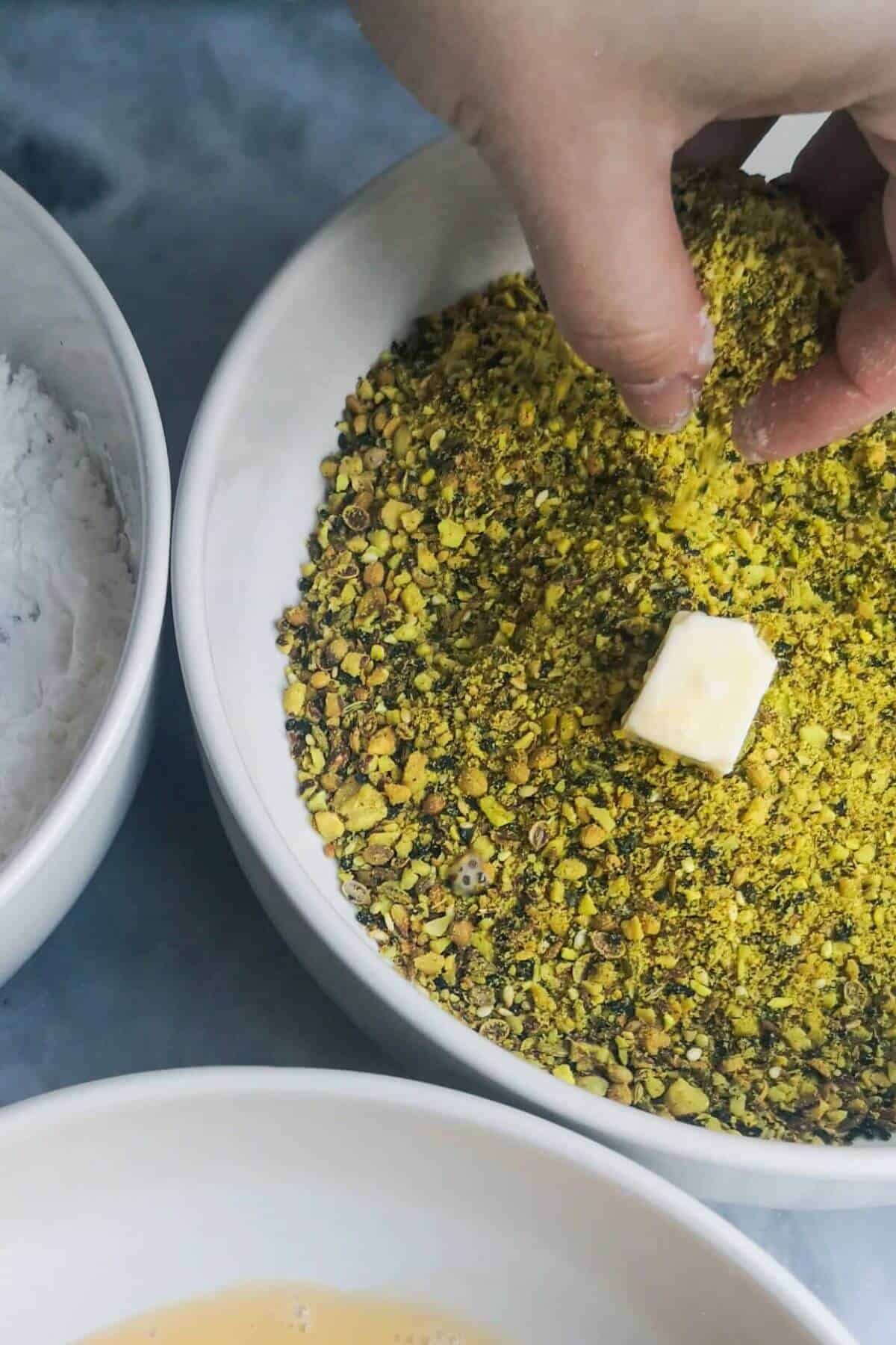 Halloumi bite being tossed in dukkah.