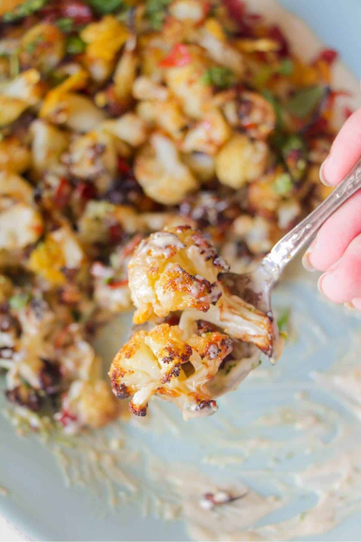 Close up of roasted parmesan cauliflower on a silver spoon.