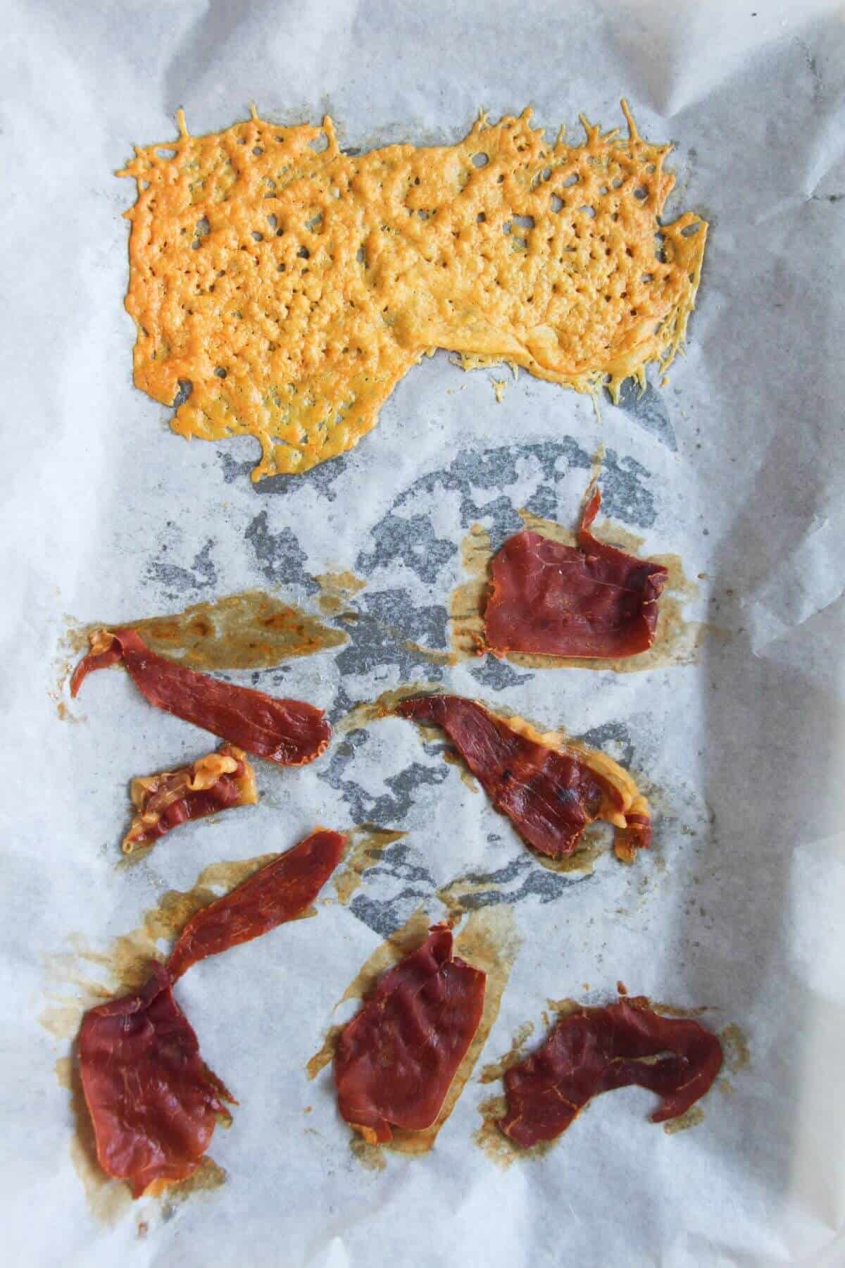 Crispy parmesan and prosciutto on a baking paper lined oven tray.