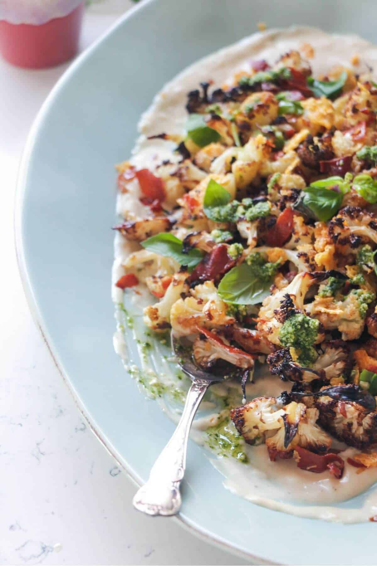 Parmesan roasted cauliflower salad on an oven blue plate with crispy parmesan and prosciutto.