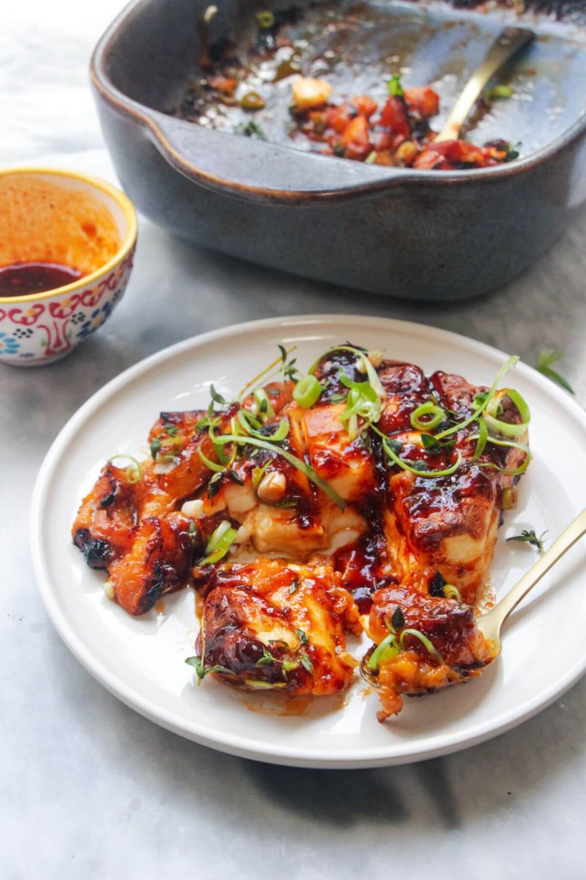 Baked whole halloumi on a small white plate with blue oven dish in the background.