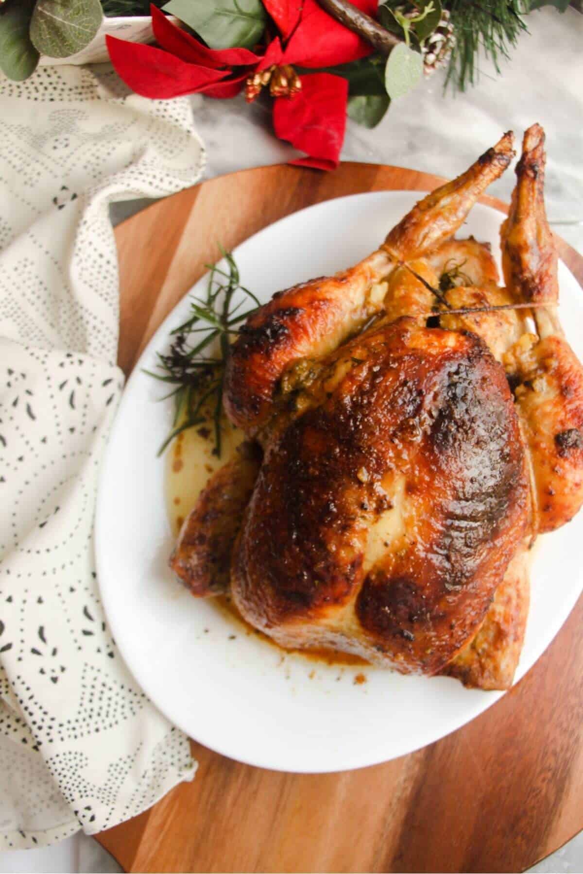Close up view of golden brown roasted chicken on a white oval plat.