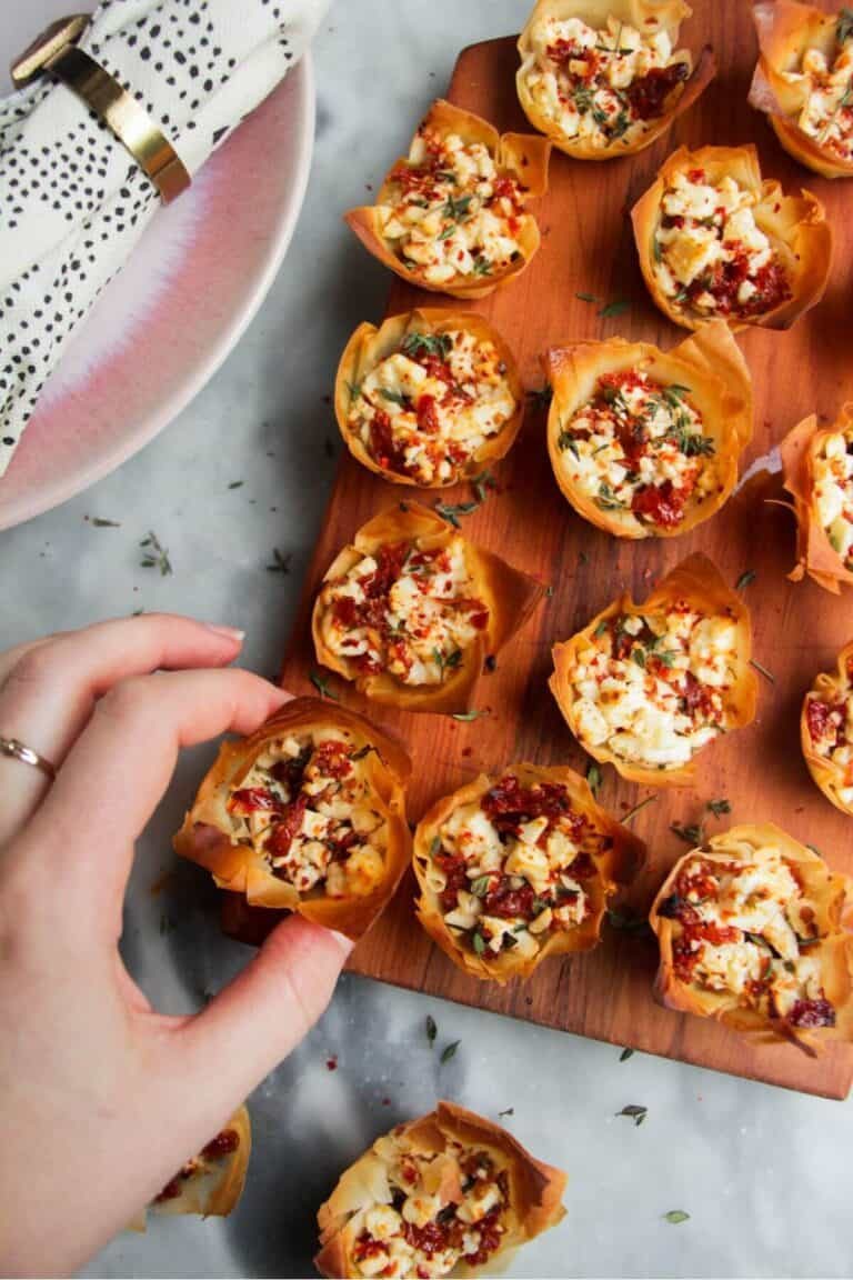 Sundried tomato and feta filo cups on a small wooden board.