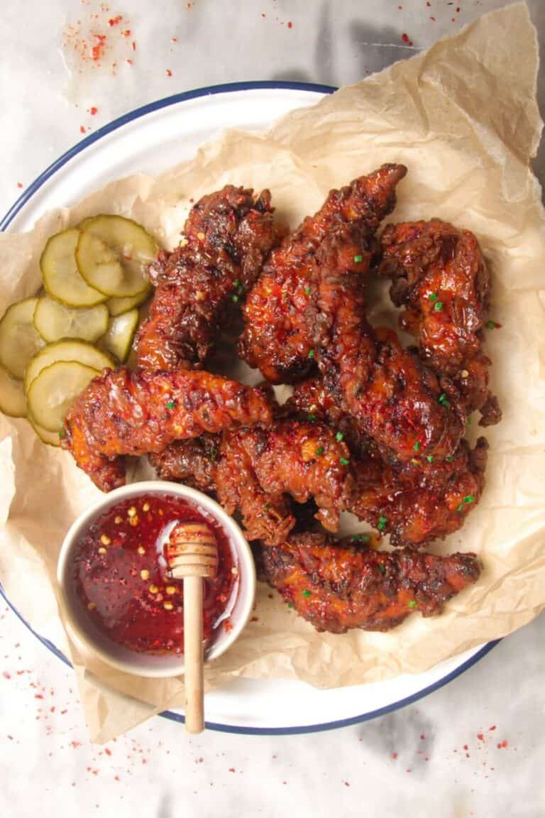 Plate of crispy hot honey chicken tenders with hot honey sauce on the side.
