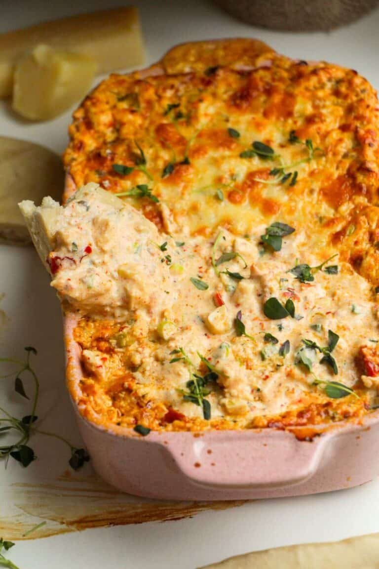 Pita bread dipped into baked dip in a baked baking dish.