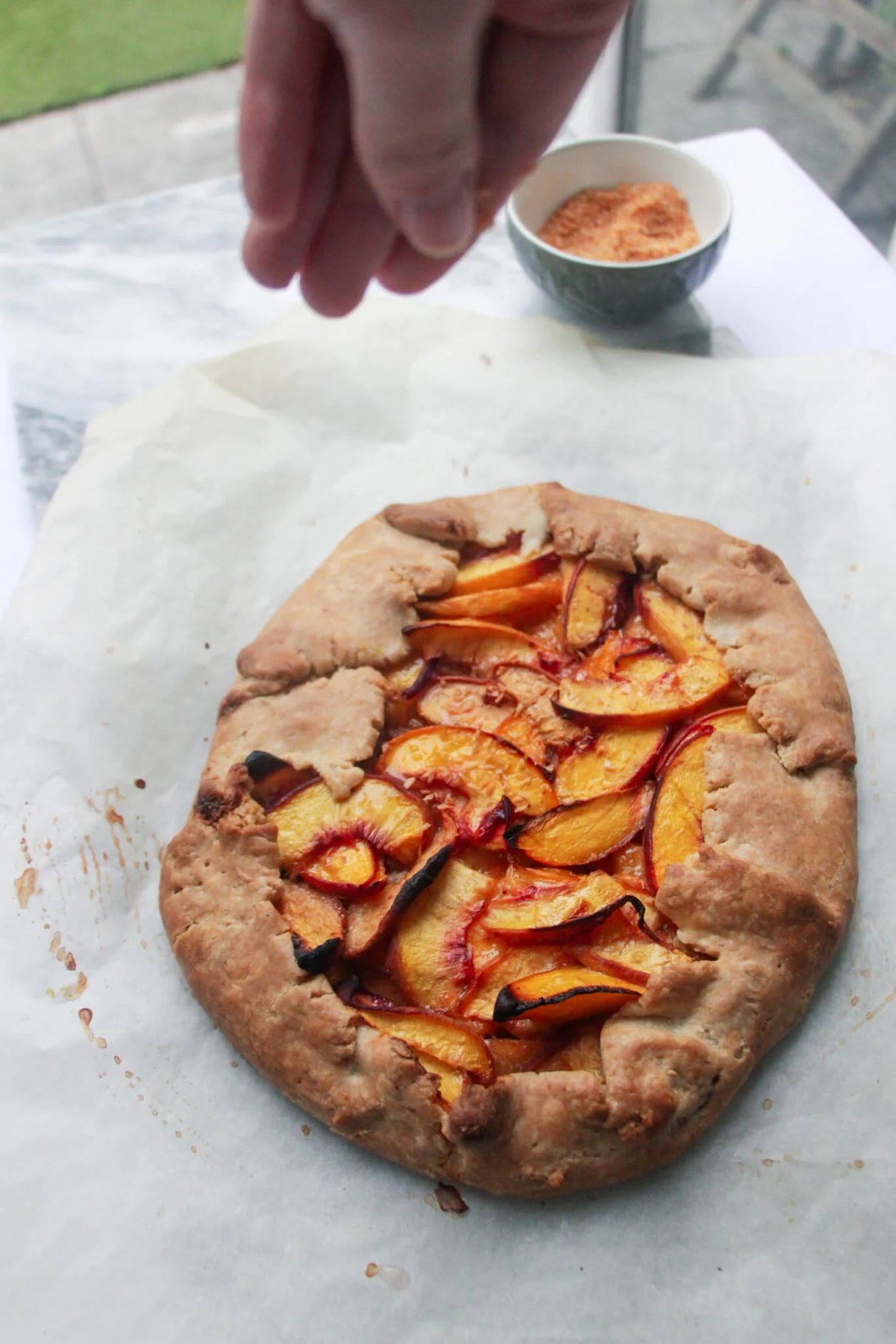 Hand sprinkling toasted coconut over peach galette.