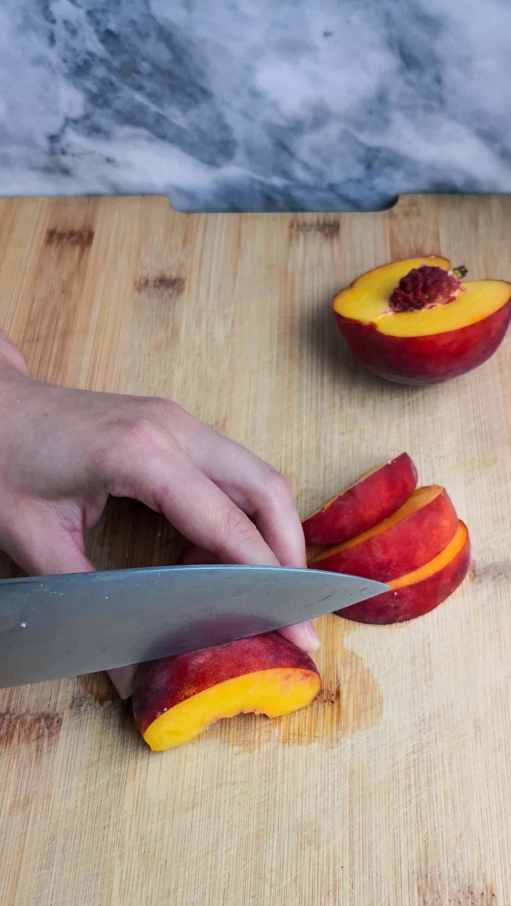 Slicing peach on a wooden board.