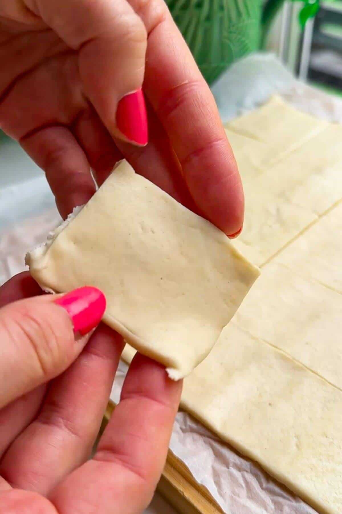 Holding square of puff pastry.