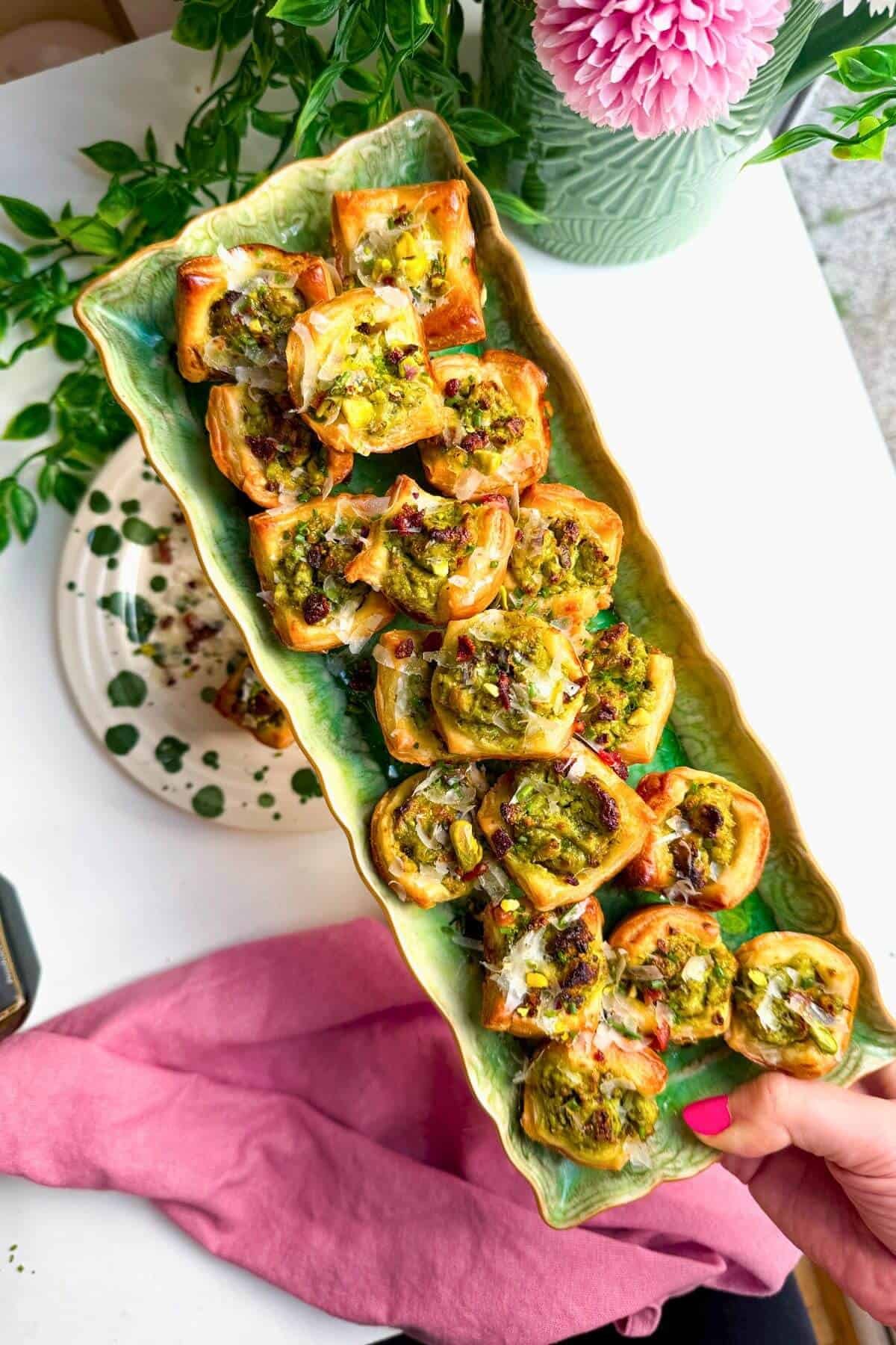 Pesto ricotta puff pastry cups laid out on serving plates.