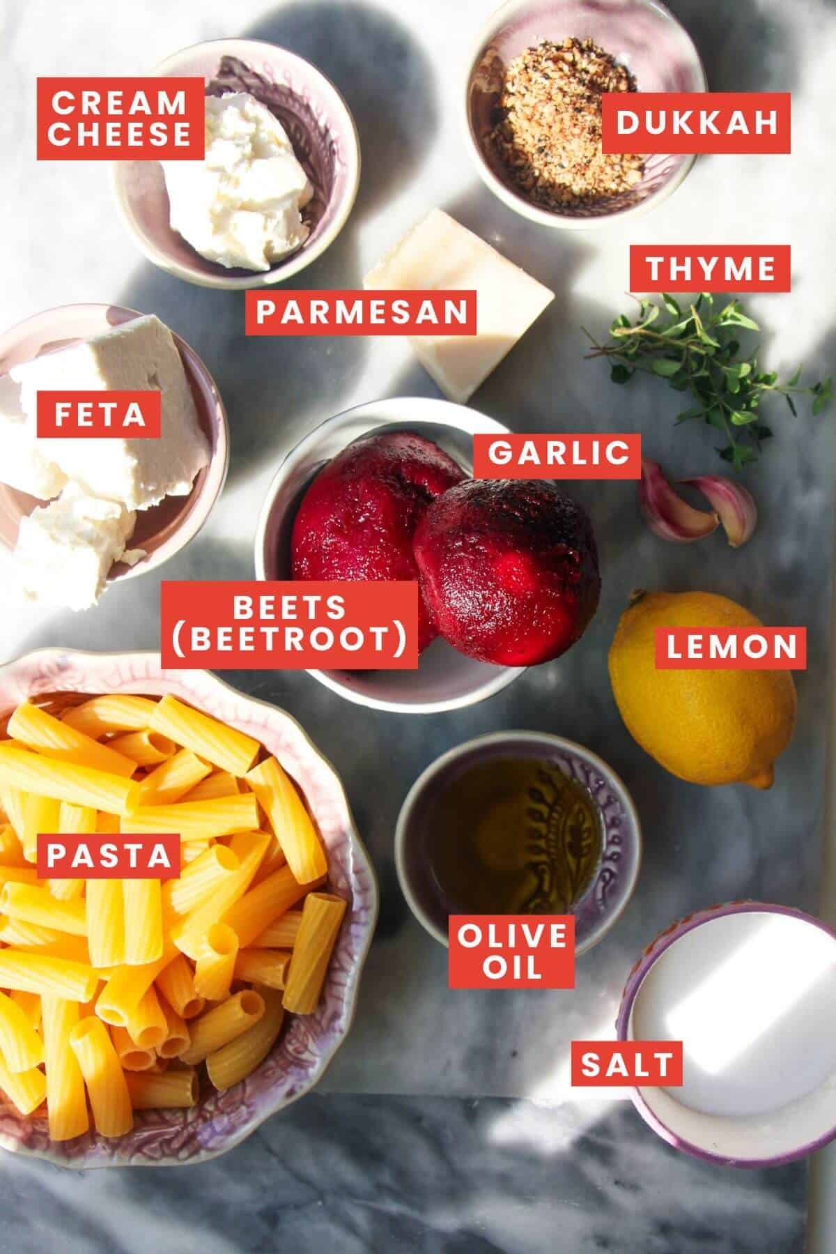 Ingredients for pink beet pasta laid out on a grey marble background and labelled.