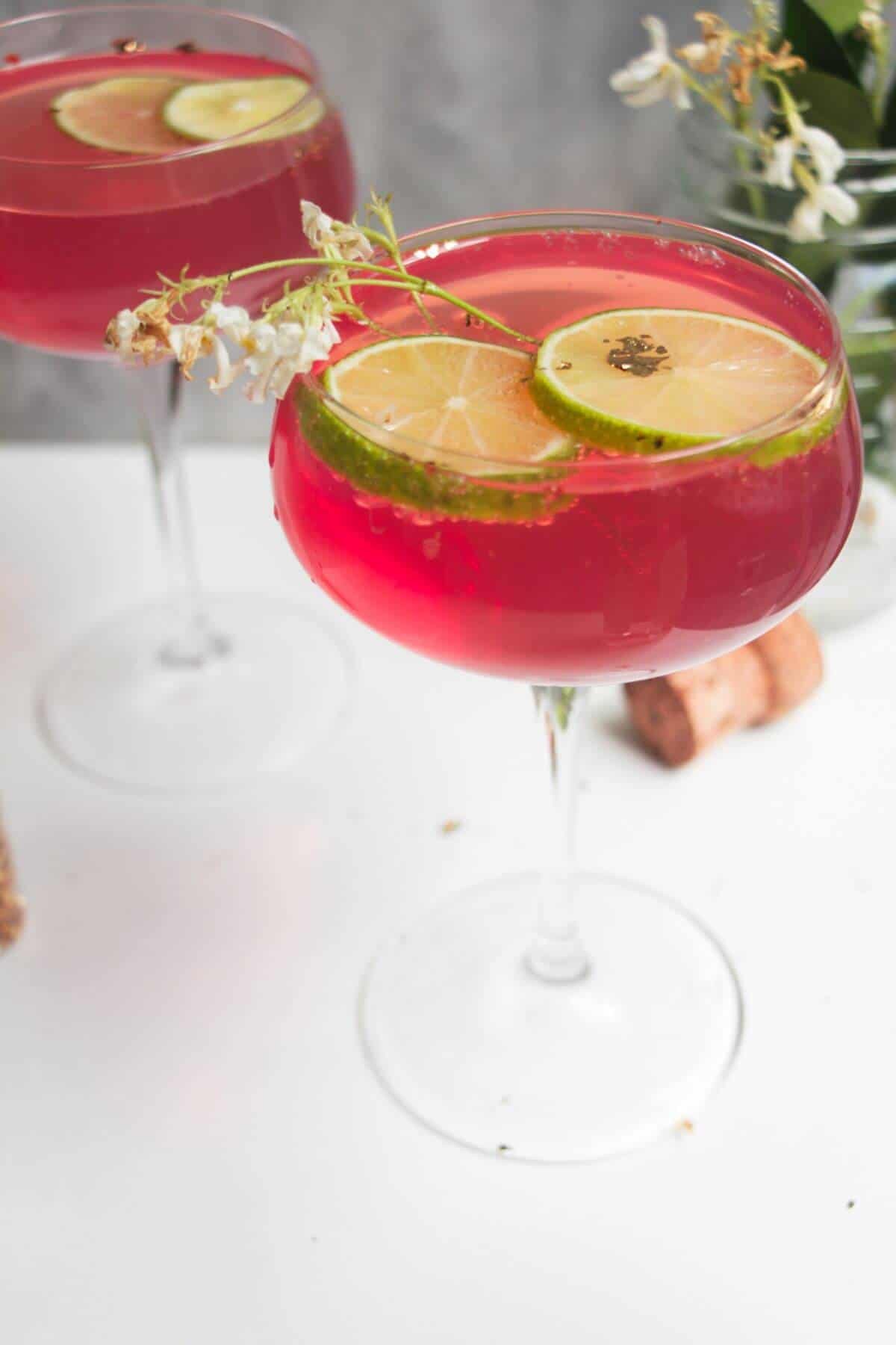 Pink Barbie spritz in a glass coupe, with another glass in the background.