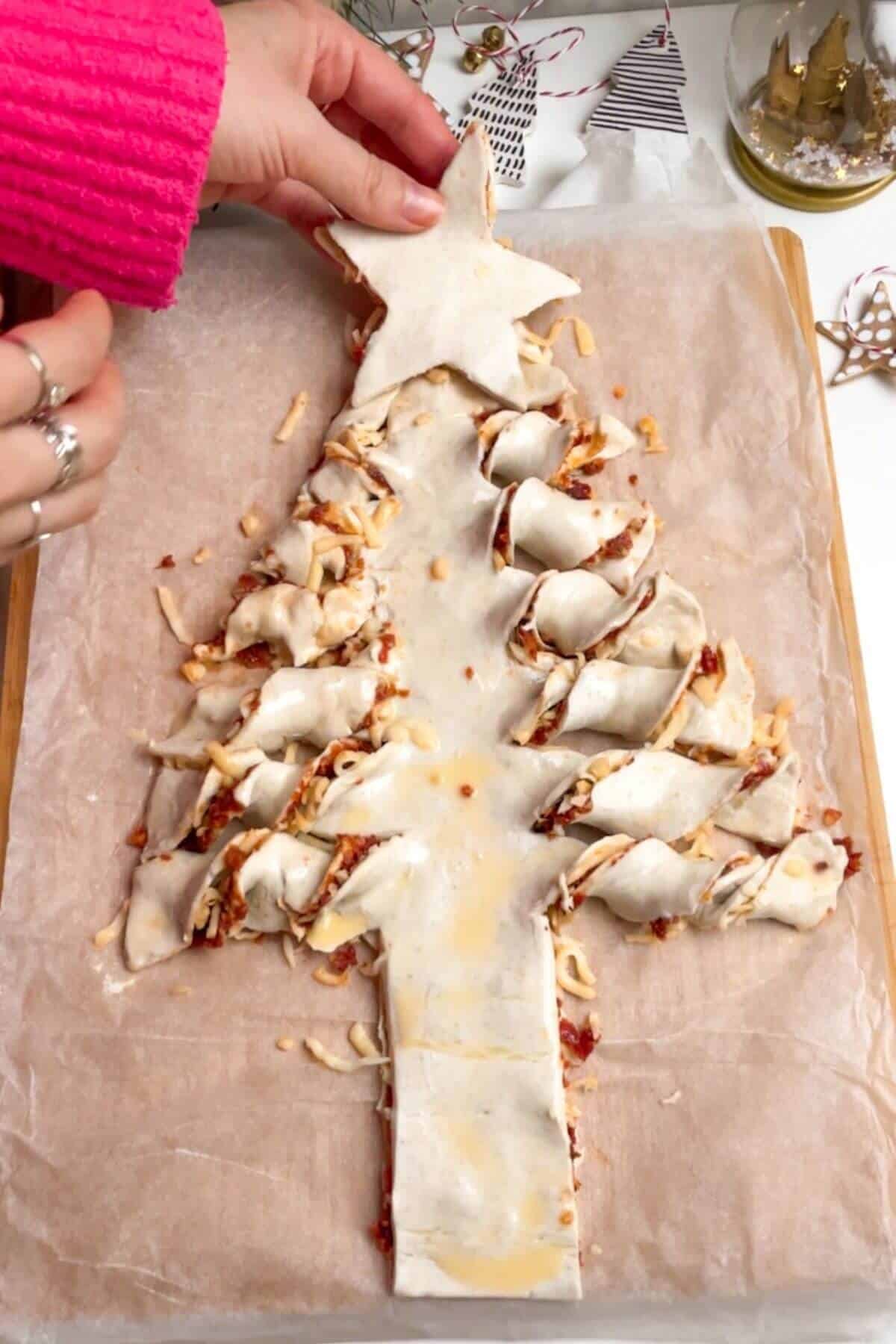 Placing puff pastry star on top of Christmas tree.