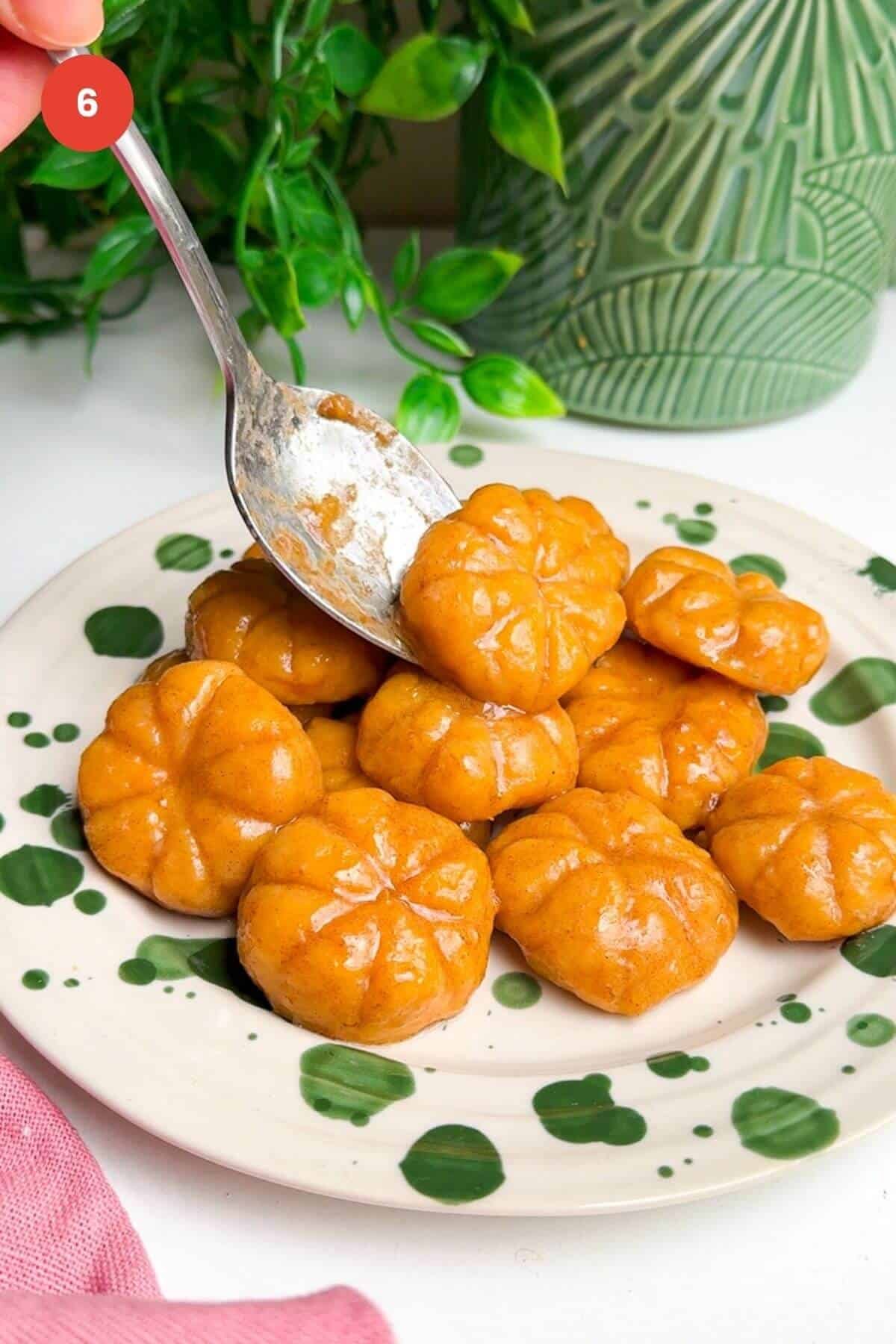 Serving brown butter pumpkin shaped gnocchi on plate.