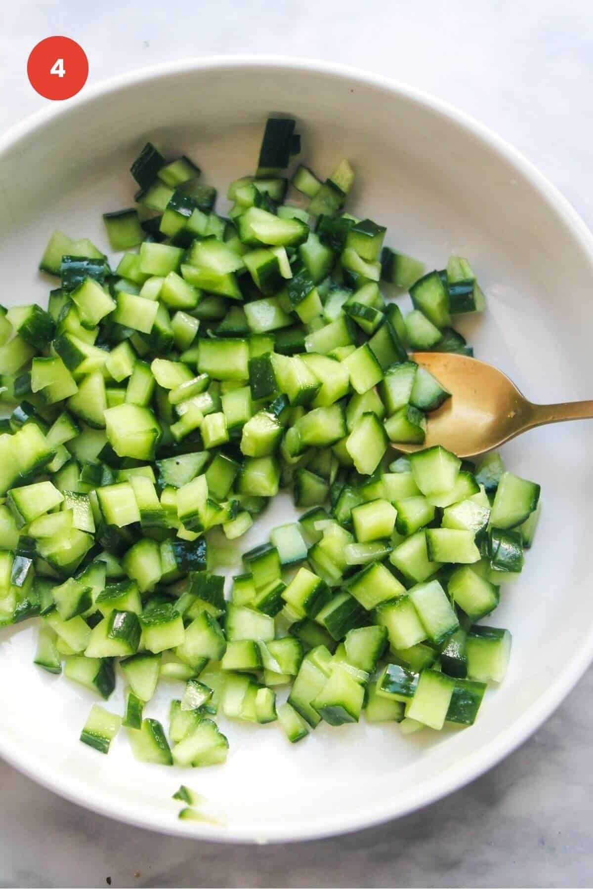 Diced cucumber in a bowl with rice vinegar and salt.