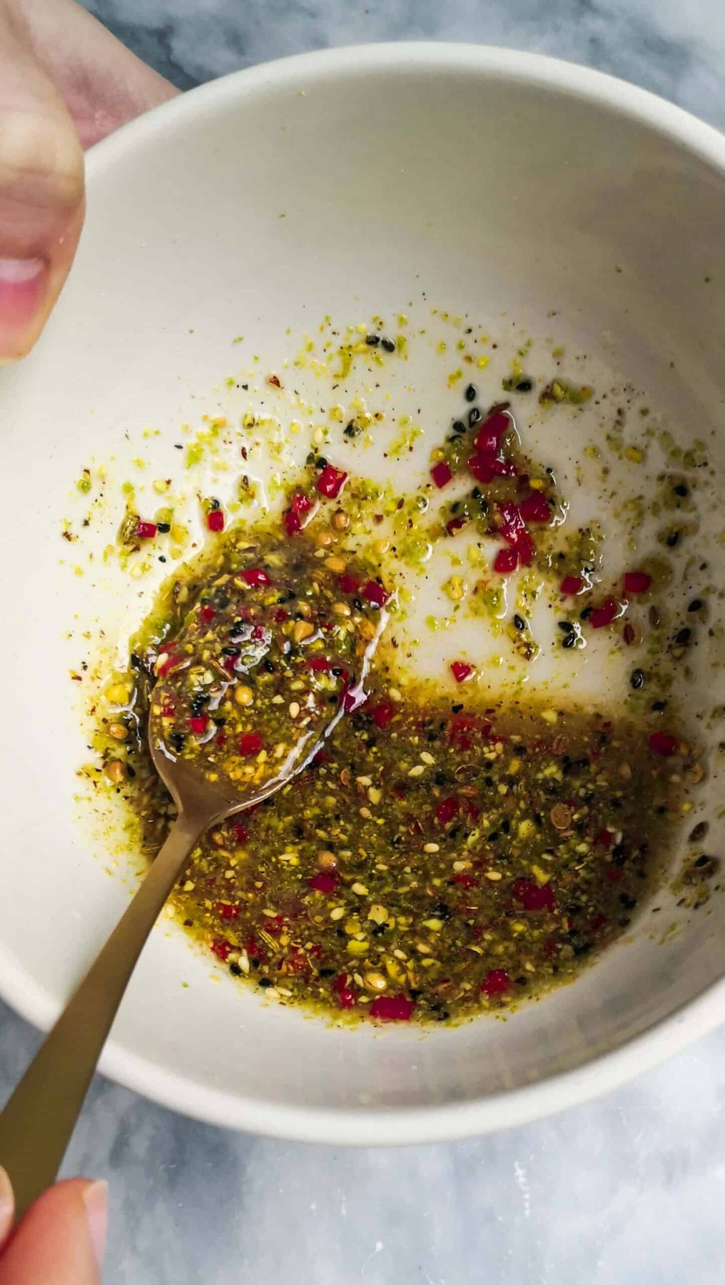 Close up of lime salsa with a small gold spoon in it in a small white bowl.