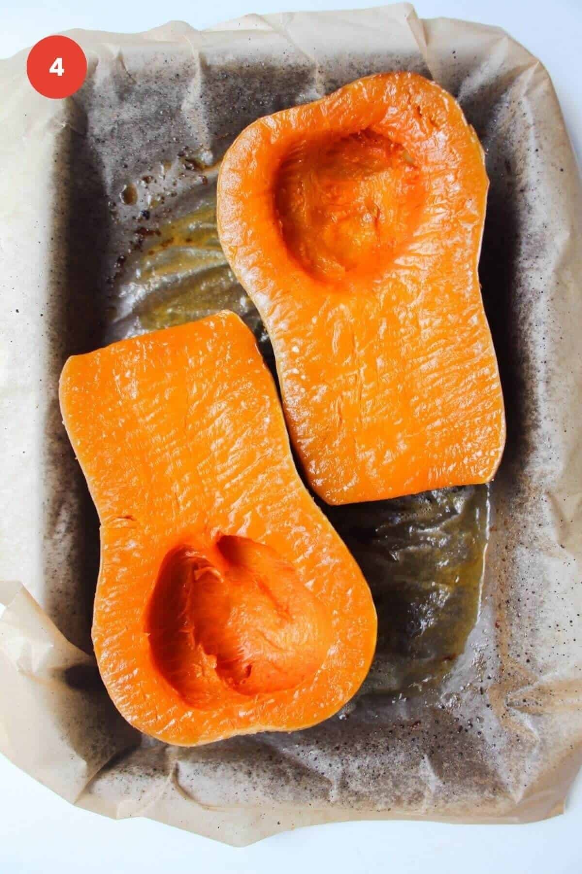 Roasted butternut squash halves on a lined oven tray.
