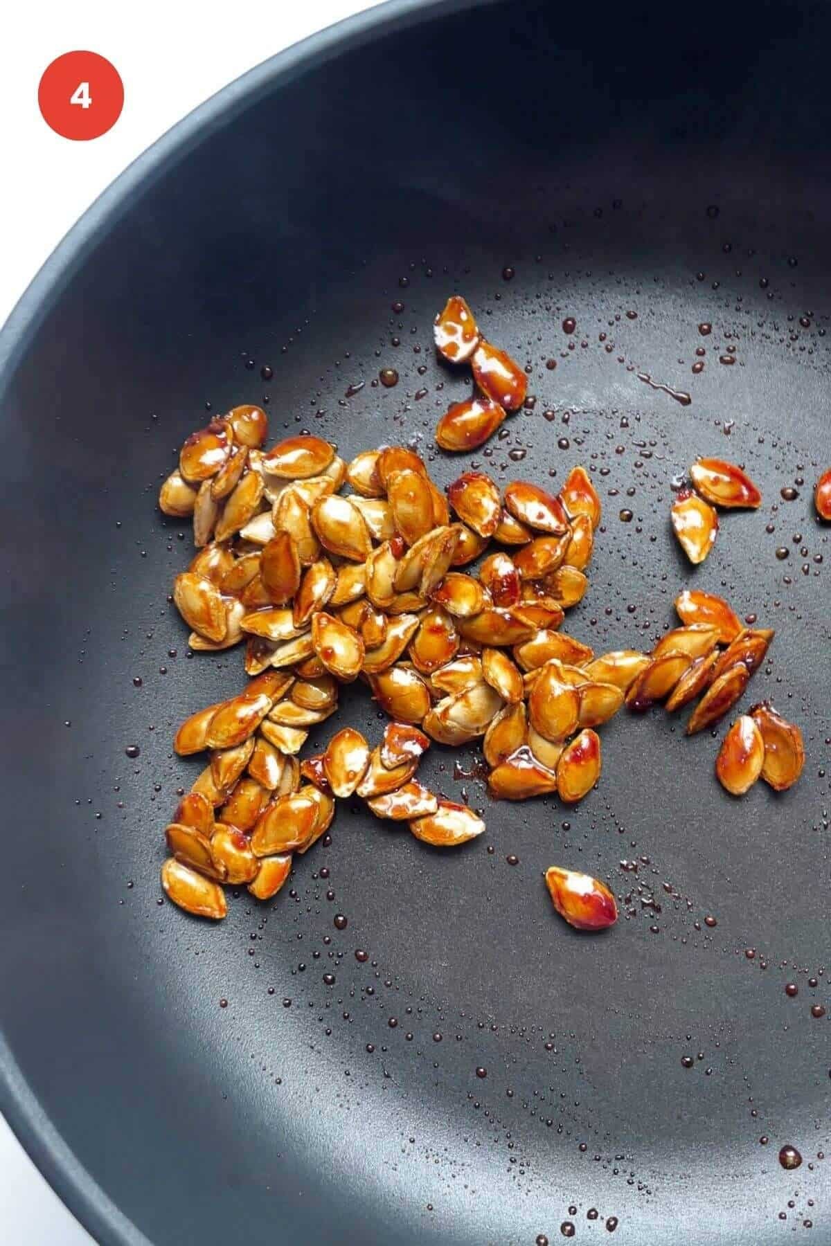 Crispy salted honey pumpkin seeds in frying pan.