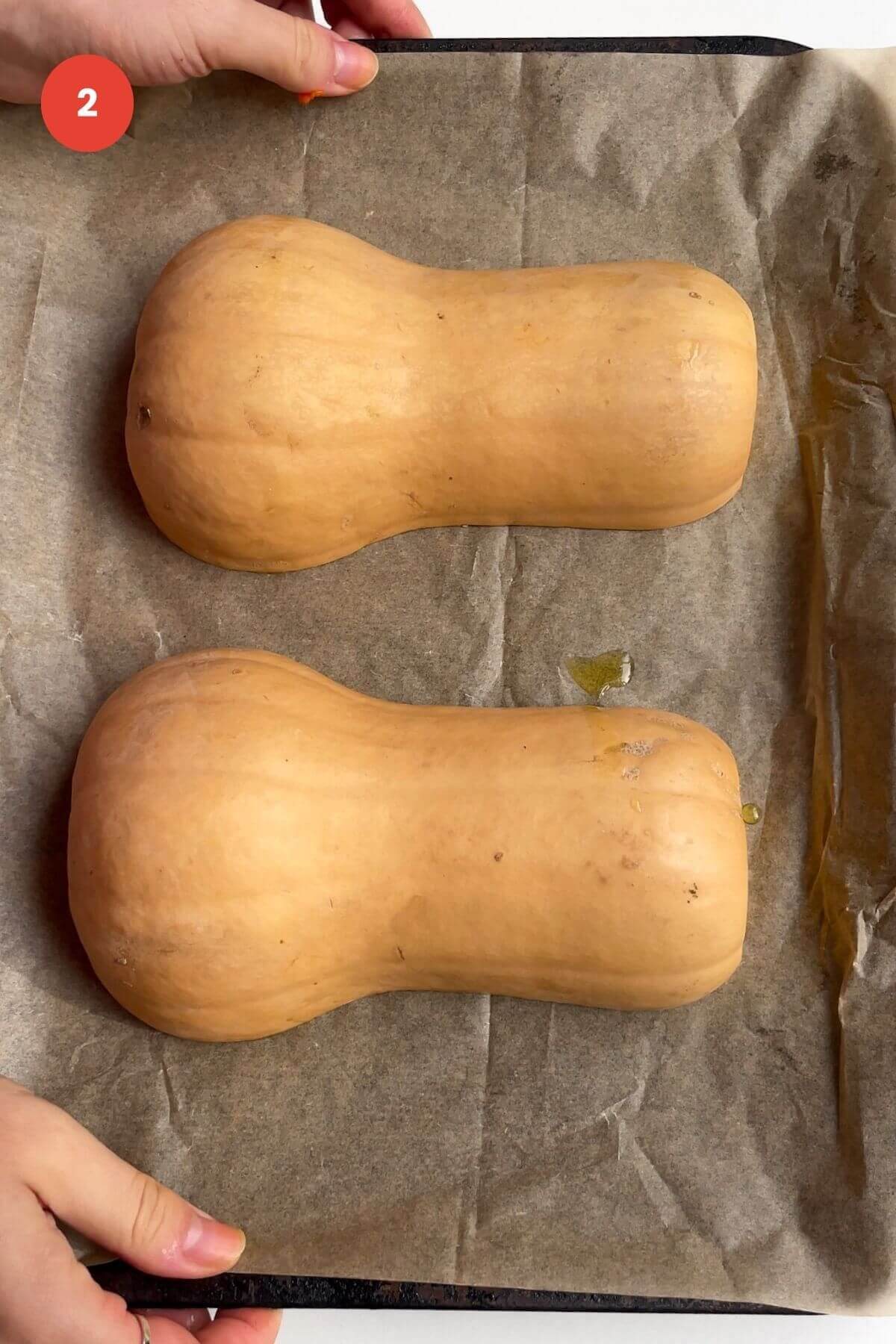Butternut squash halves set on lined oven tray.
