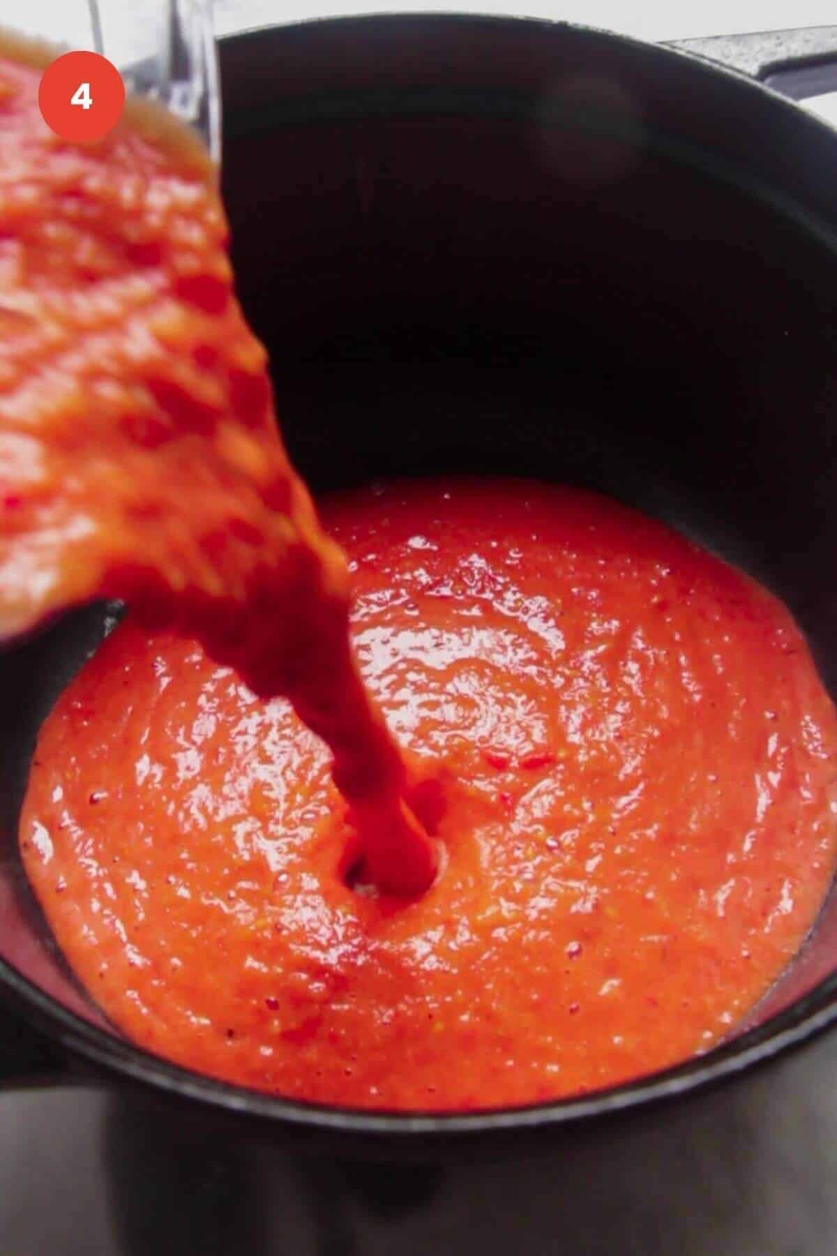 Tomato soup being poured into a large pot.