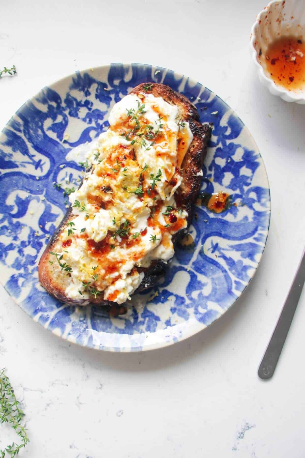 Burrata on a piece of toasted sourdough with hot honey and thyme on top.