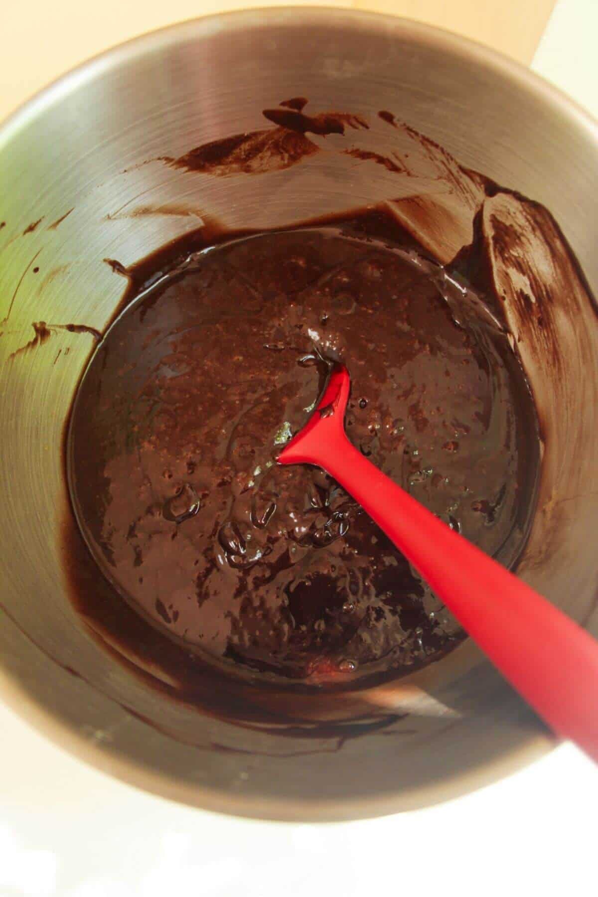 Chocolate mixed with eggs and butter in bowl.