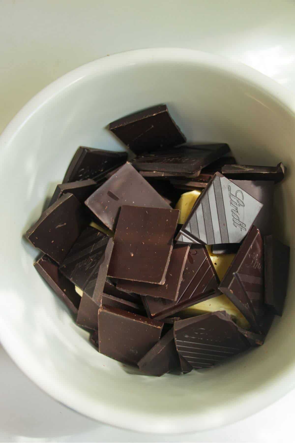 Dark chocolate and butter in a white mixing bowl.